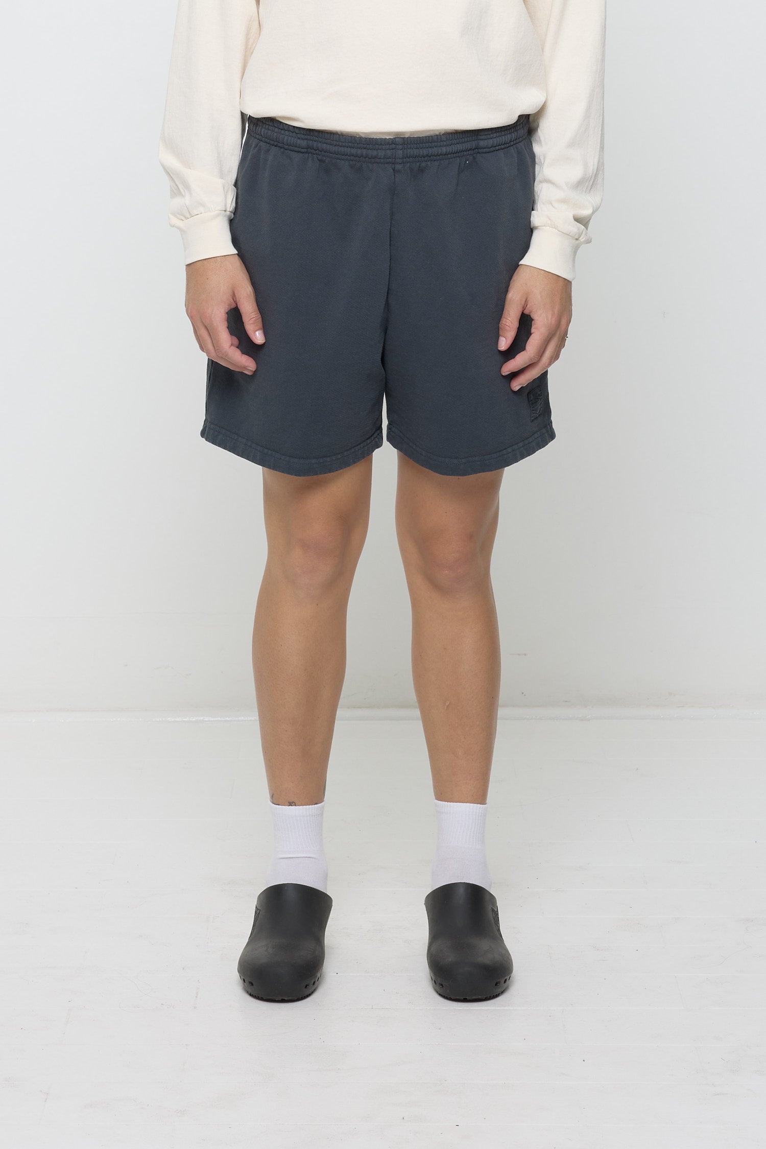 Slate Trash Fleece Everyday Shorts on model, front. Relaxed fit, elastic waist, small logo patch on left thigh.
