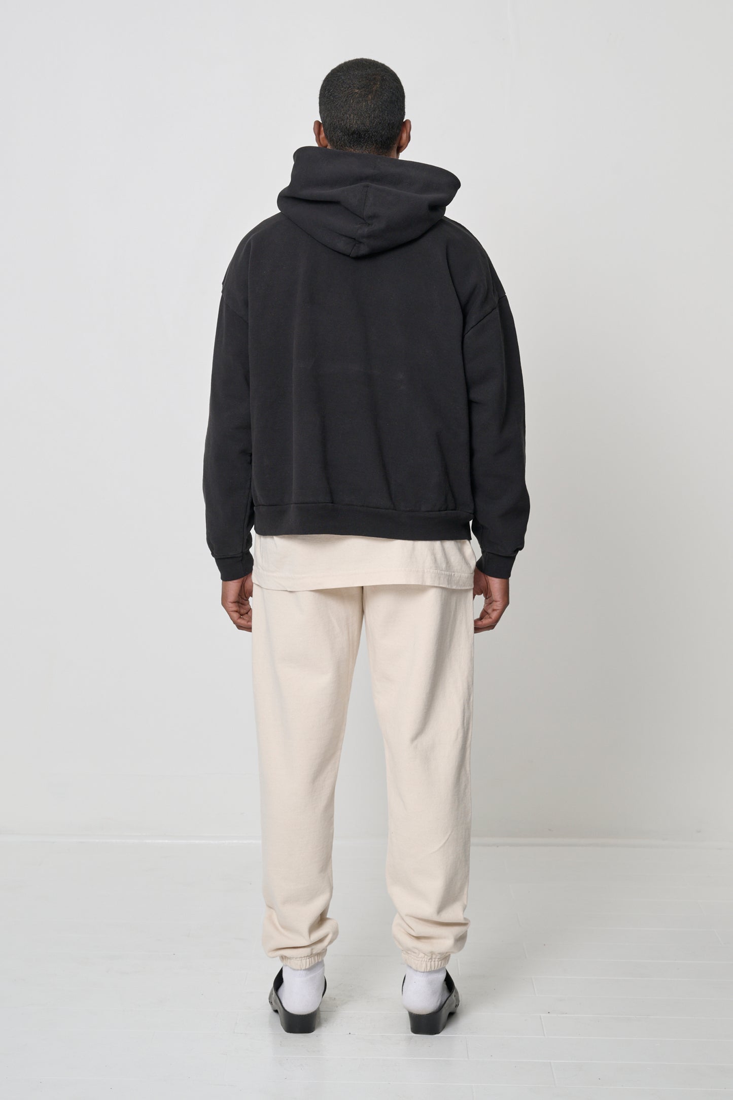 Back view: Man wearing Black Trash Hoodie, highlighting the hood.
