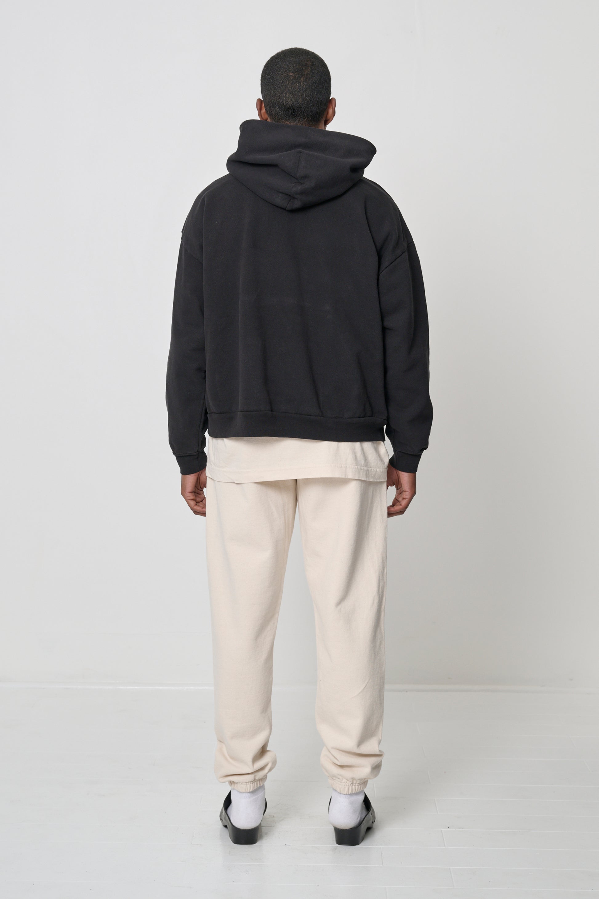 Back view: Man wearing Black Trash Hoodie, highlighting the hood.
