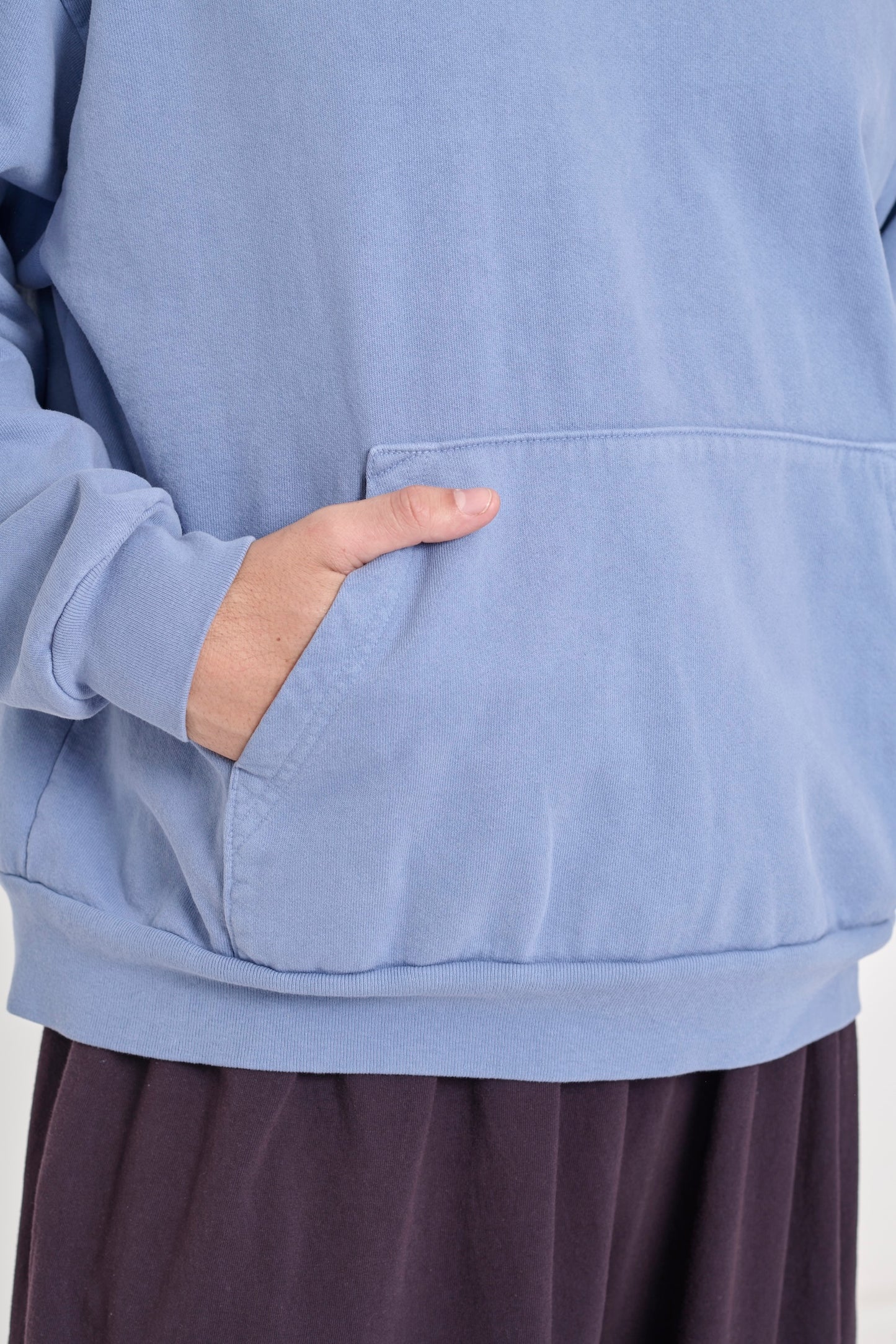 Zoomed in detail of a person's hand in the large front kangaroo pocket on a Periwinkle Trash Hoodie.
