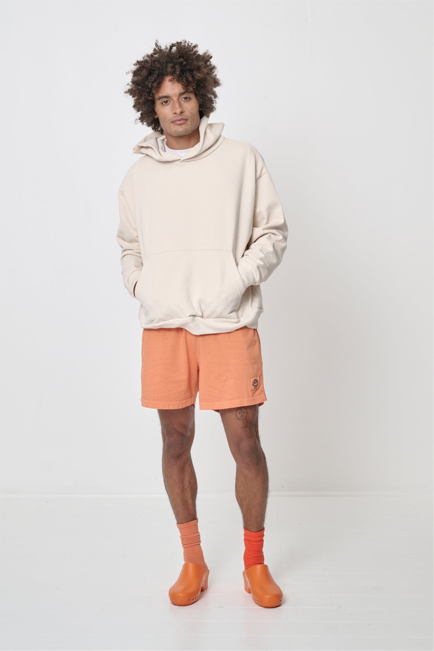 Front full length view: man wearing a Scour Trash Hoodie with hands in the kangaroo pocket.