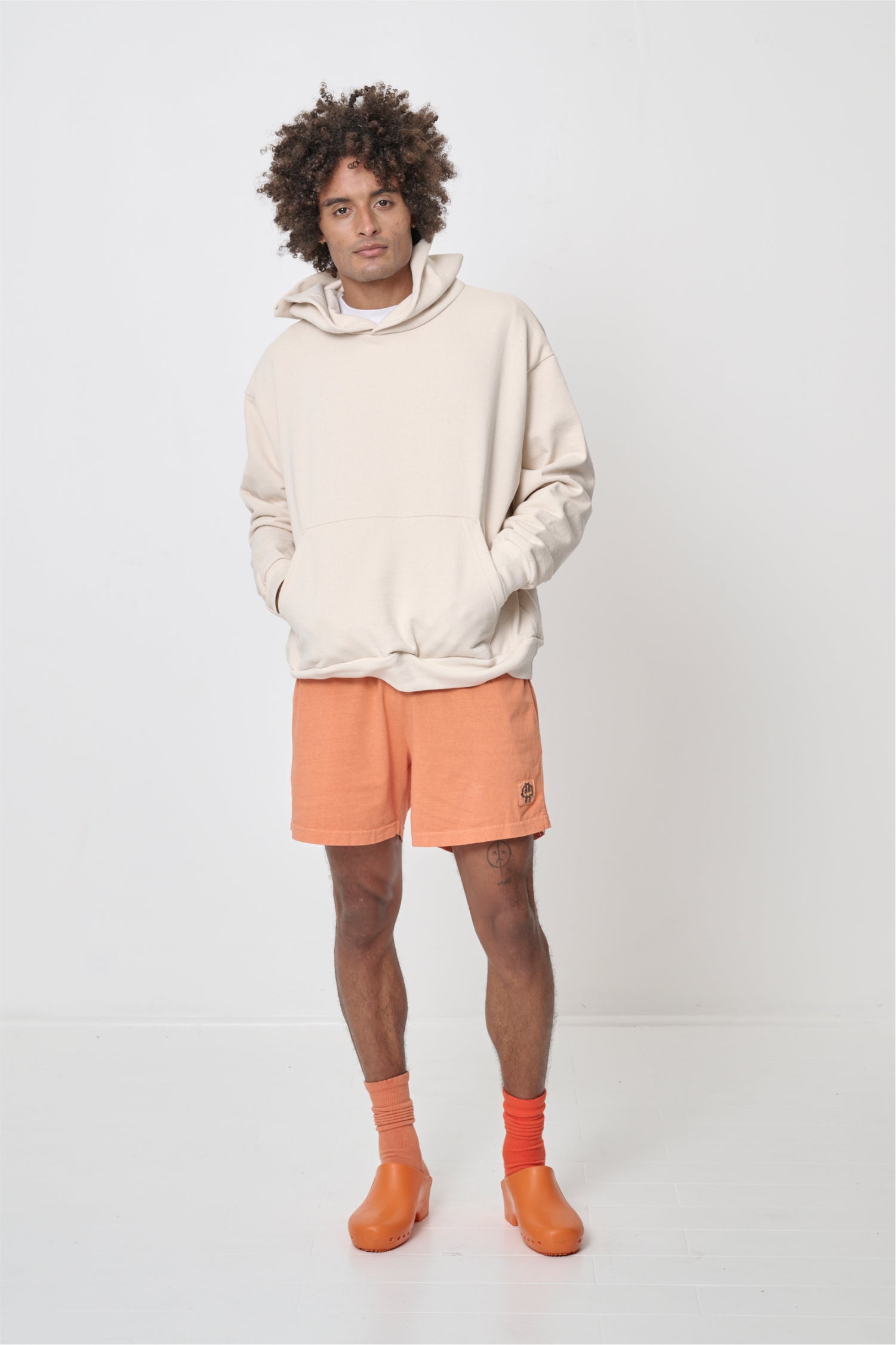 Front full length view: man wearing a Scour Trash Hoodie with hands in the kangaroo pocket.