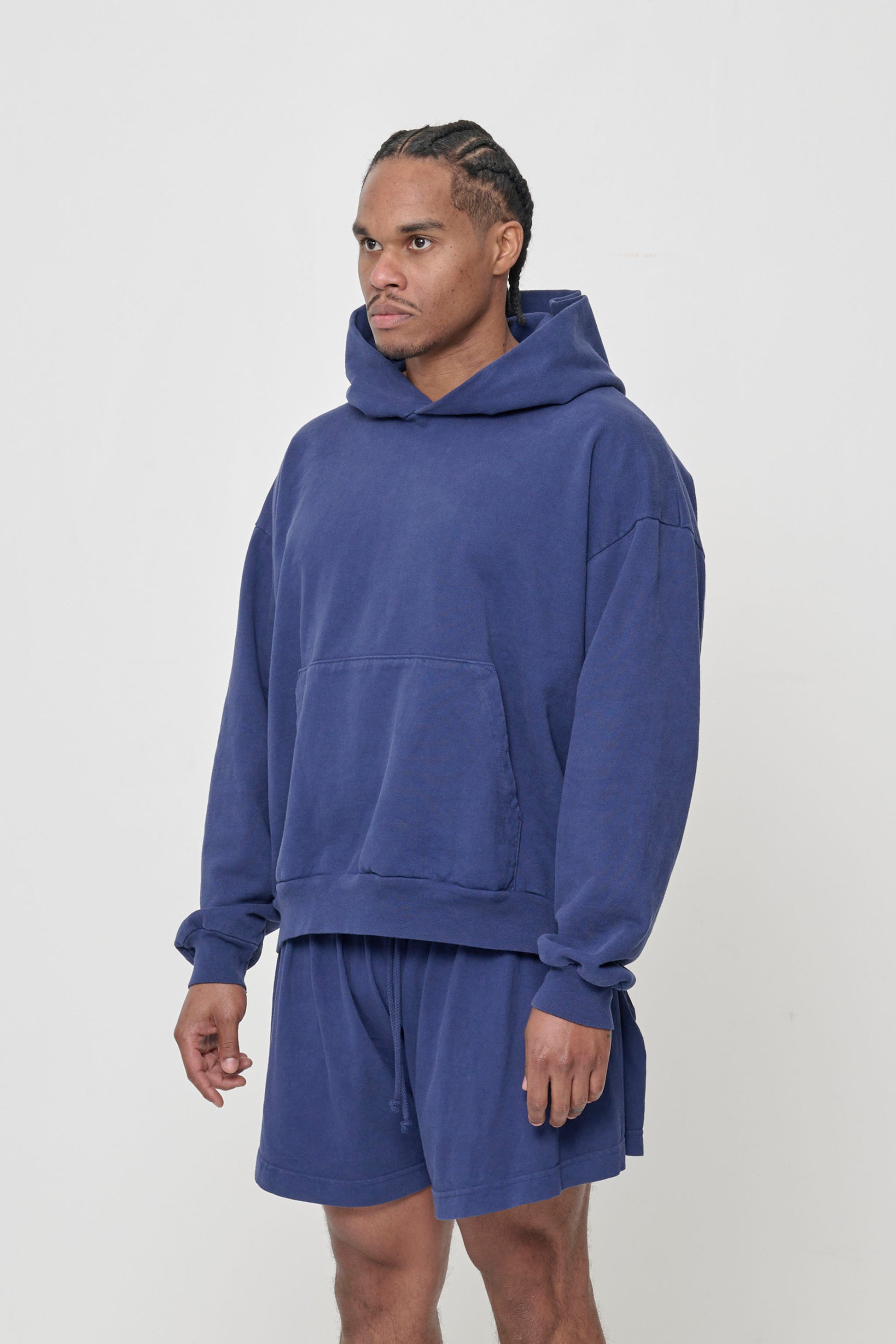 3/4 front view of a man wearing a Washed Navy Trash Hoodie, showcasing sleeve's relaxed fit and drop shoulder.
