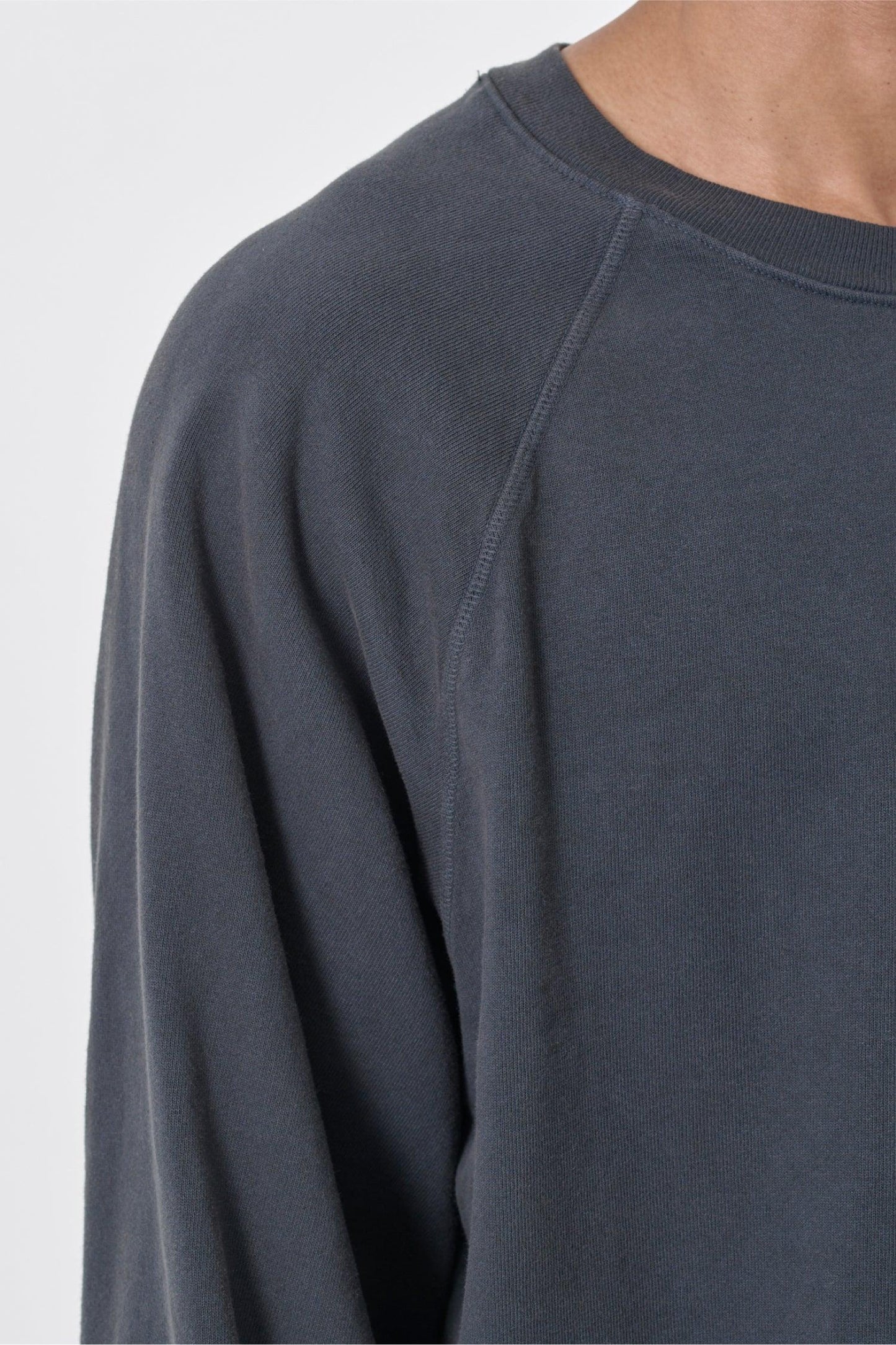 Zoom in on shoulder of person wearing a Slate Trash Raglan, highlighting the raglan stitching and rib neckband.