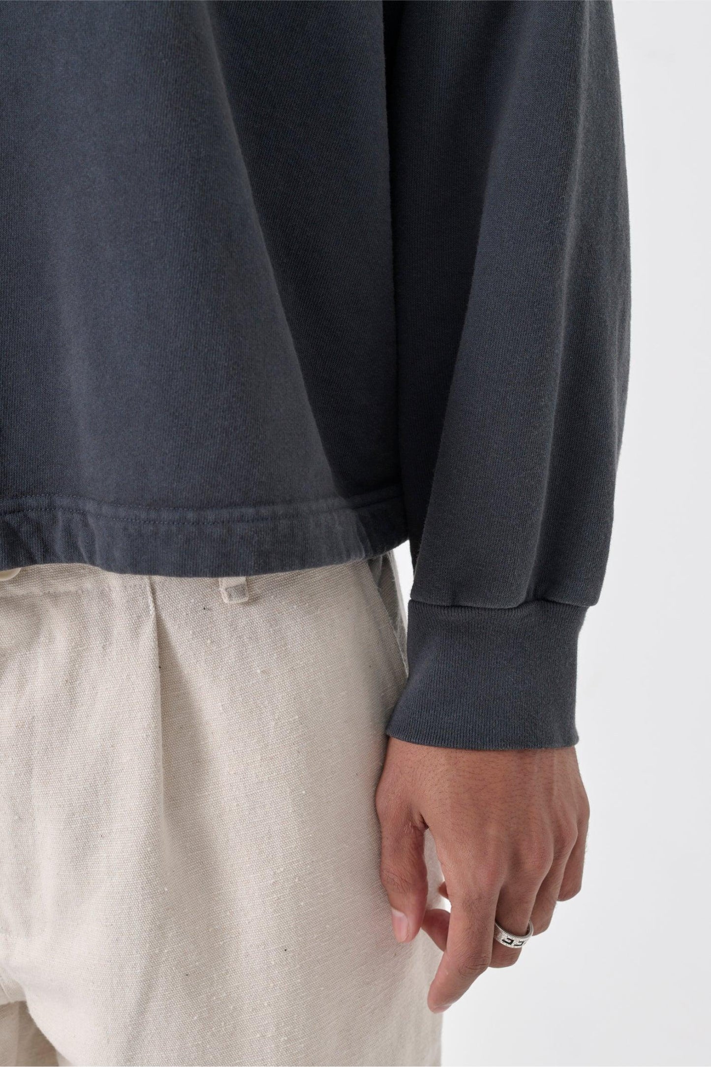 Zoom in on lower-right part of a person wearing a Slate Trash Raglan, highlighting the heavy hem and rib cuff.