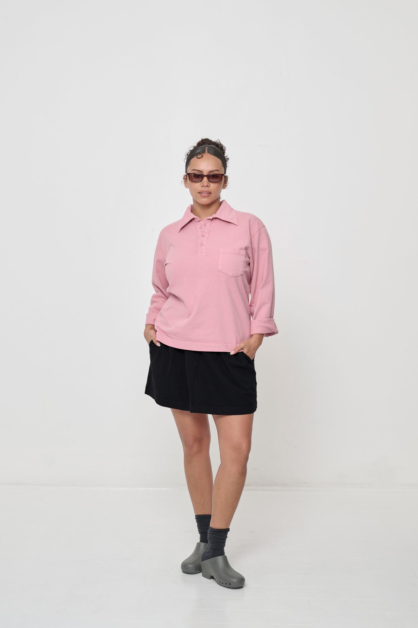 Woman wearing a Wild Rose Rugby Trash Polo with hands in the side pockets of the Black Trash Skirt.