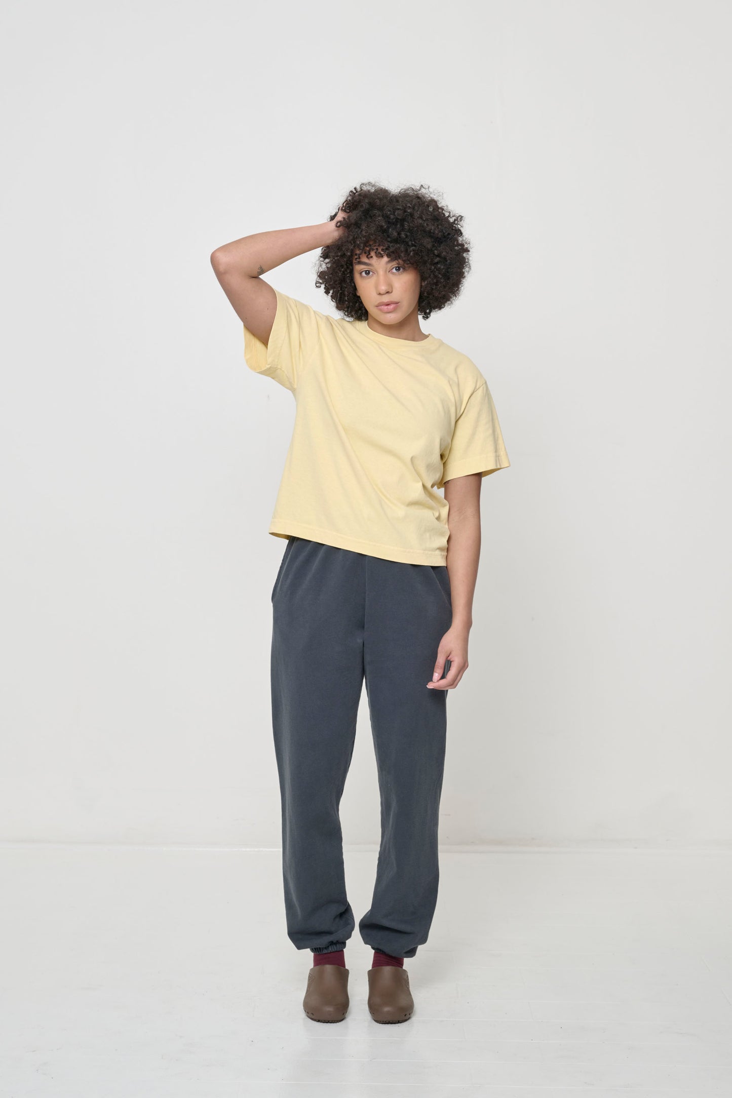 Woman with one hand on her head, wearing French Butter Boxier Trash Tee and Slate Trash Sweatpants