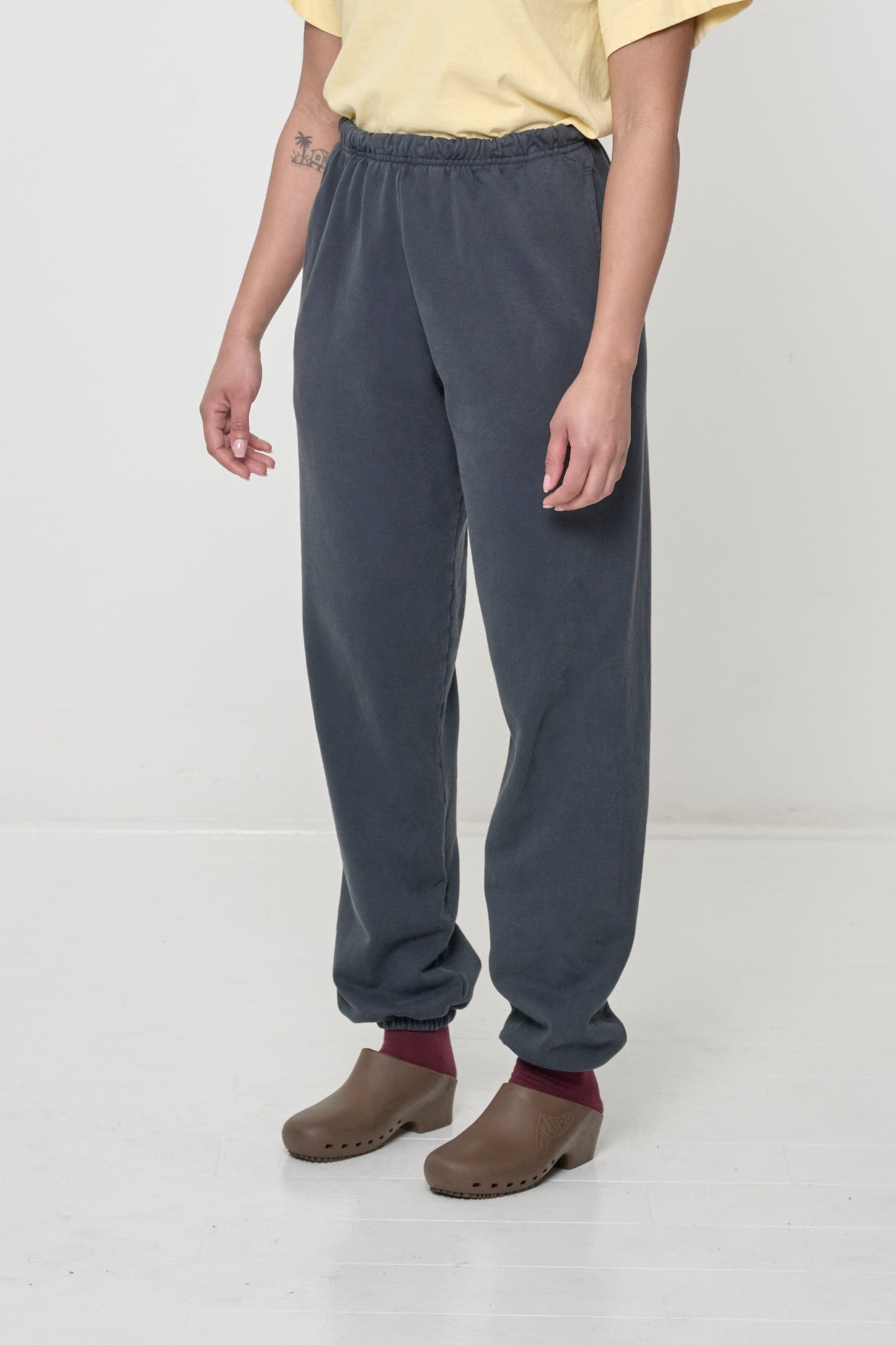 Person turned 45 degrees, wearing Slate Trash Sweatpants, inseam and side pockets.
