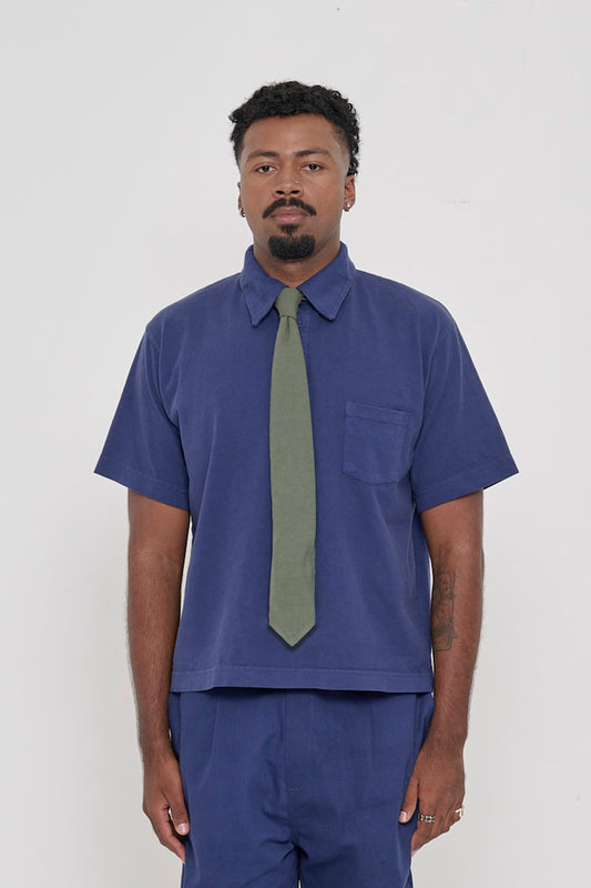 A person wearing a Pine Trash Tie with a Washed Navy Trash Polo.
