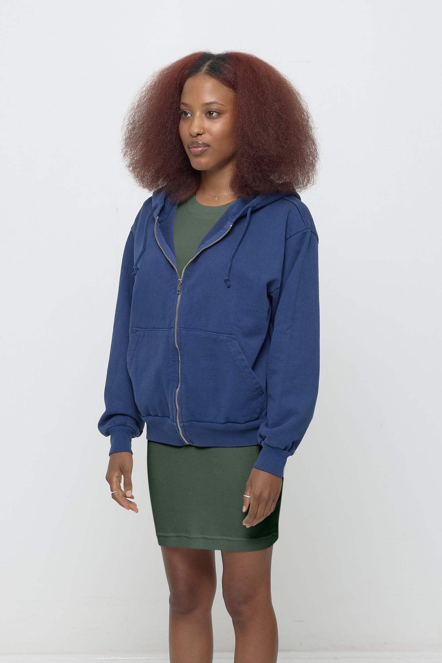 Woman facing 45-degrees, wearing a Washed Navy Trash Zip Up Hoodie, showcasing sleeve's relaxed fit and drop shoulder.