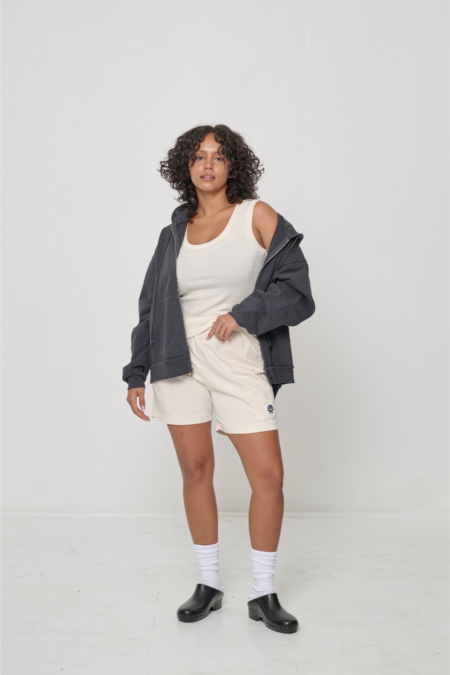 Front view: woman wearing an unzipped Slate Trash Zip Up Hoodie with left side worn off the shoulder.