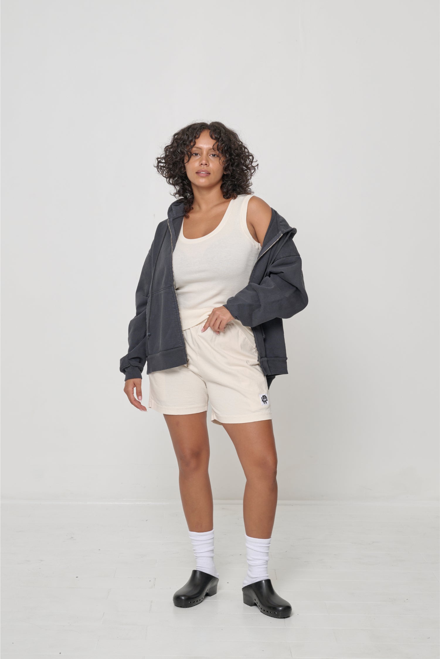 Front view: woman wearing an unzipped Slate Trash Zip Up Hoodie with left side worn off the shoulder.