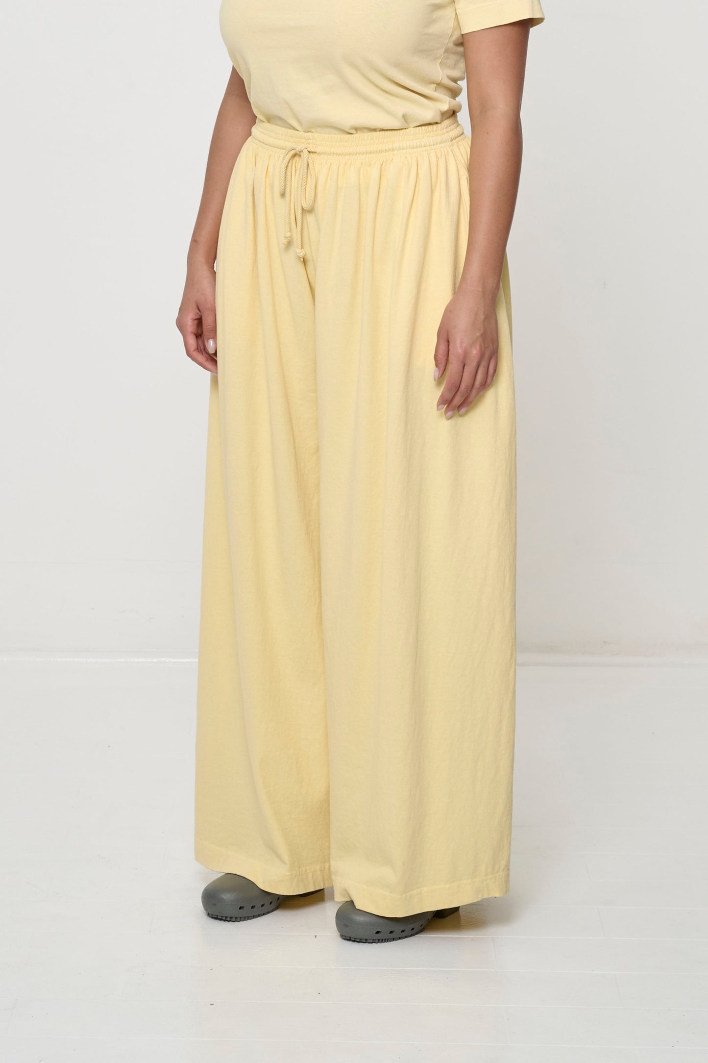 Person facing 45-degrees to the front in French Butter Tubular Pants, showing lack of side seams and flowing wide pant legs.