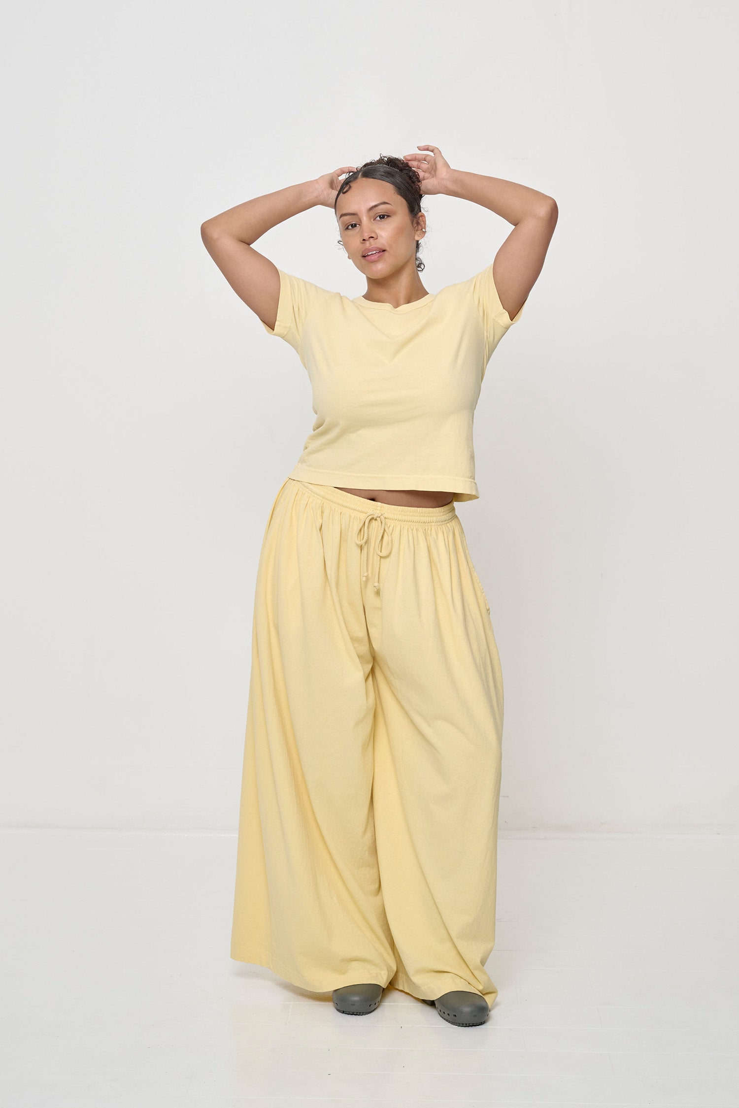 Woman with knee popped, showing the width and movement of the French Butter Tubular Pants.