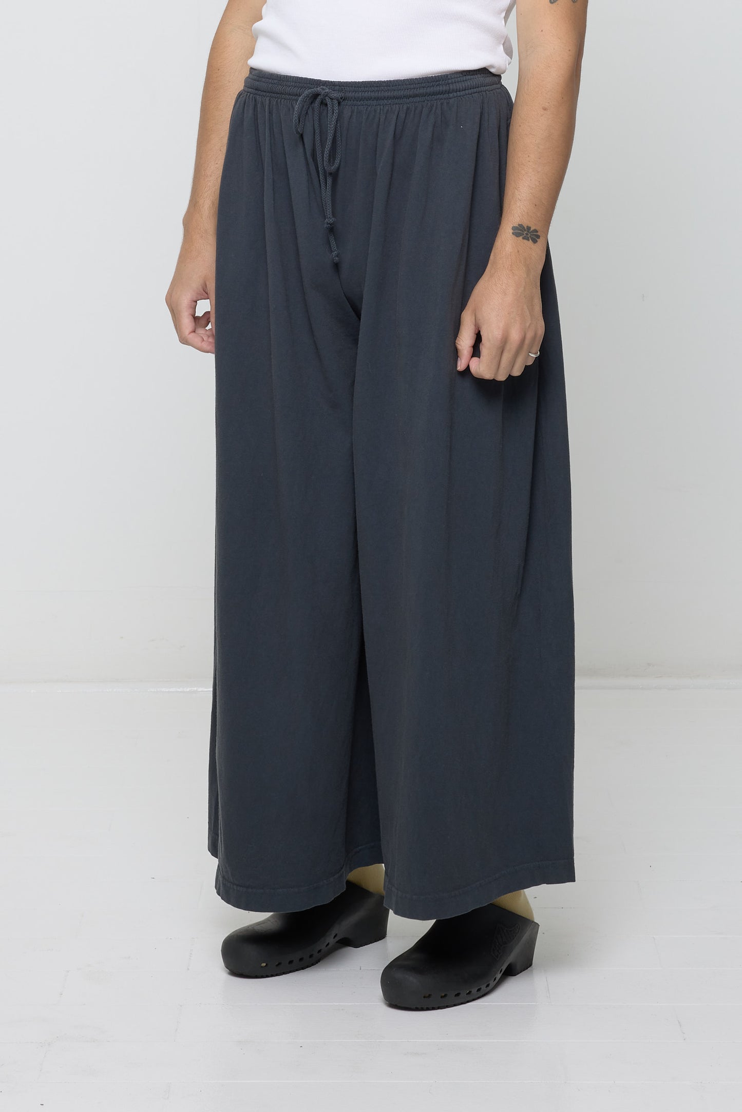 Person facing 45-degrees to the front in Slate Tubular Pants, showing lack of side seams and flowing wide pant legs.