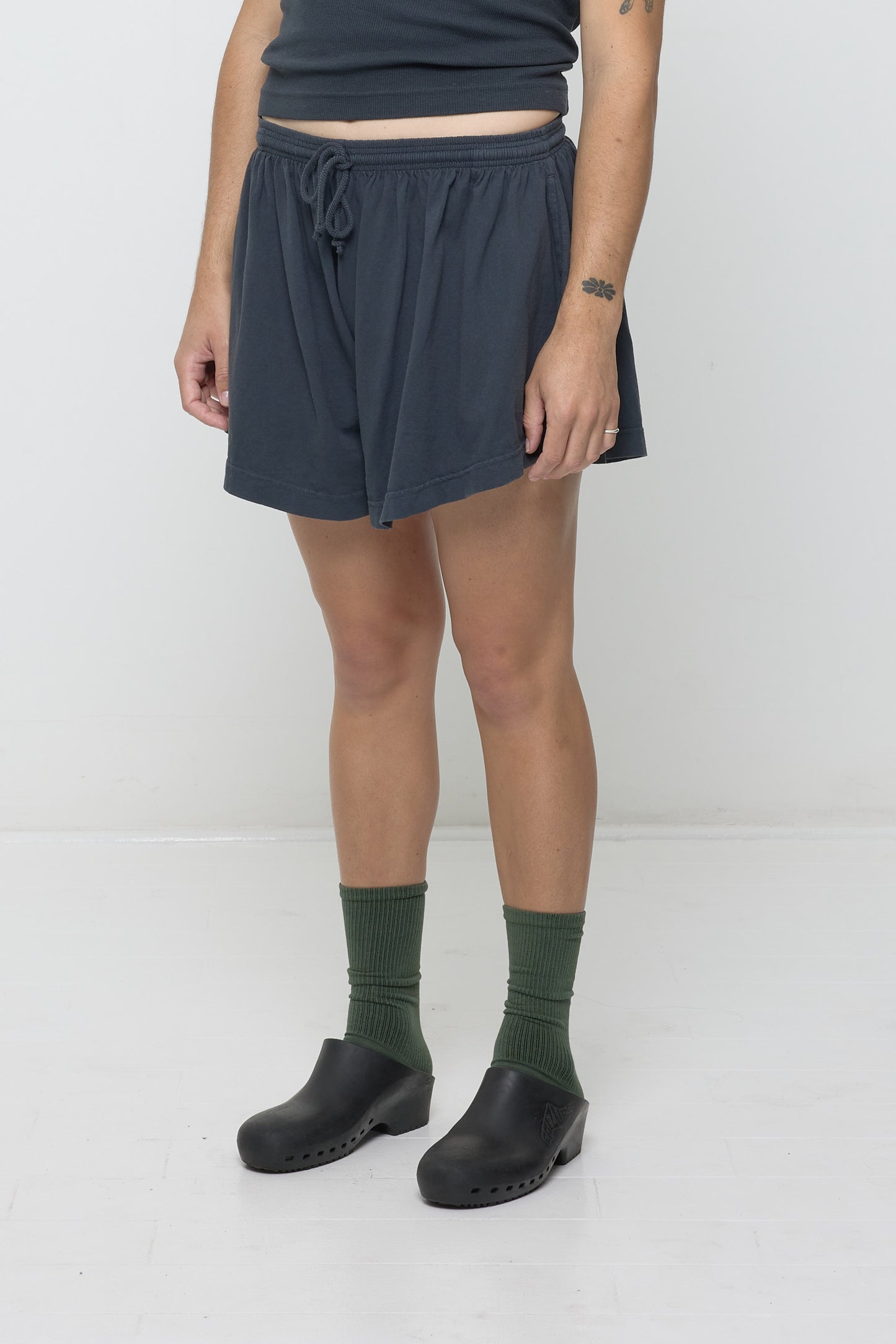 Person facing 45-degrees to the front in Slate Tubular Shorts, showing lack of side seams and shorter side hem.