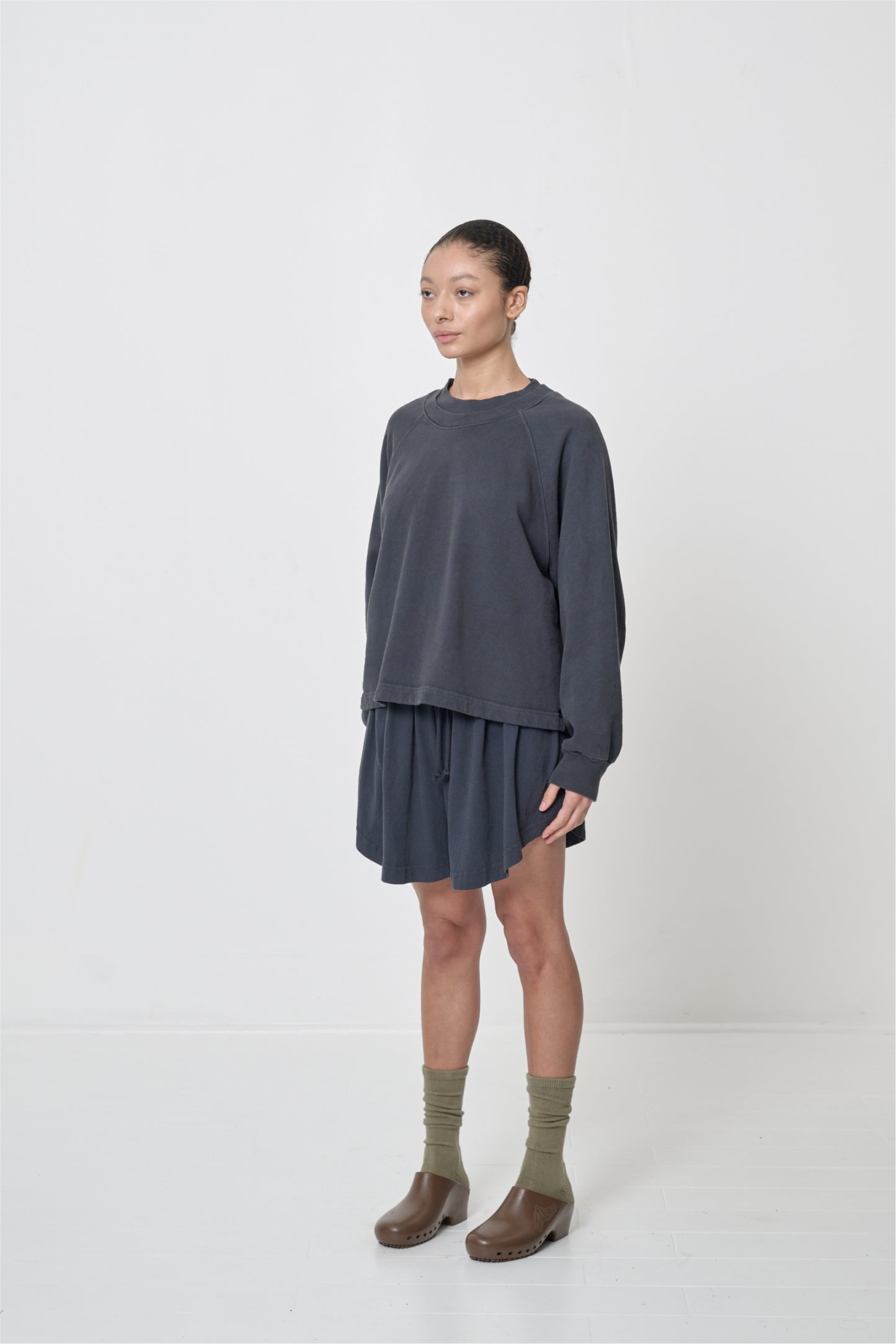 Person facing 45-degrees to the front in matching Slate Trash Raglan and Tubular Shorts and Brown Calzuro Classic Clogs.