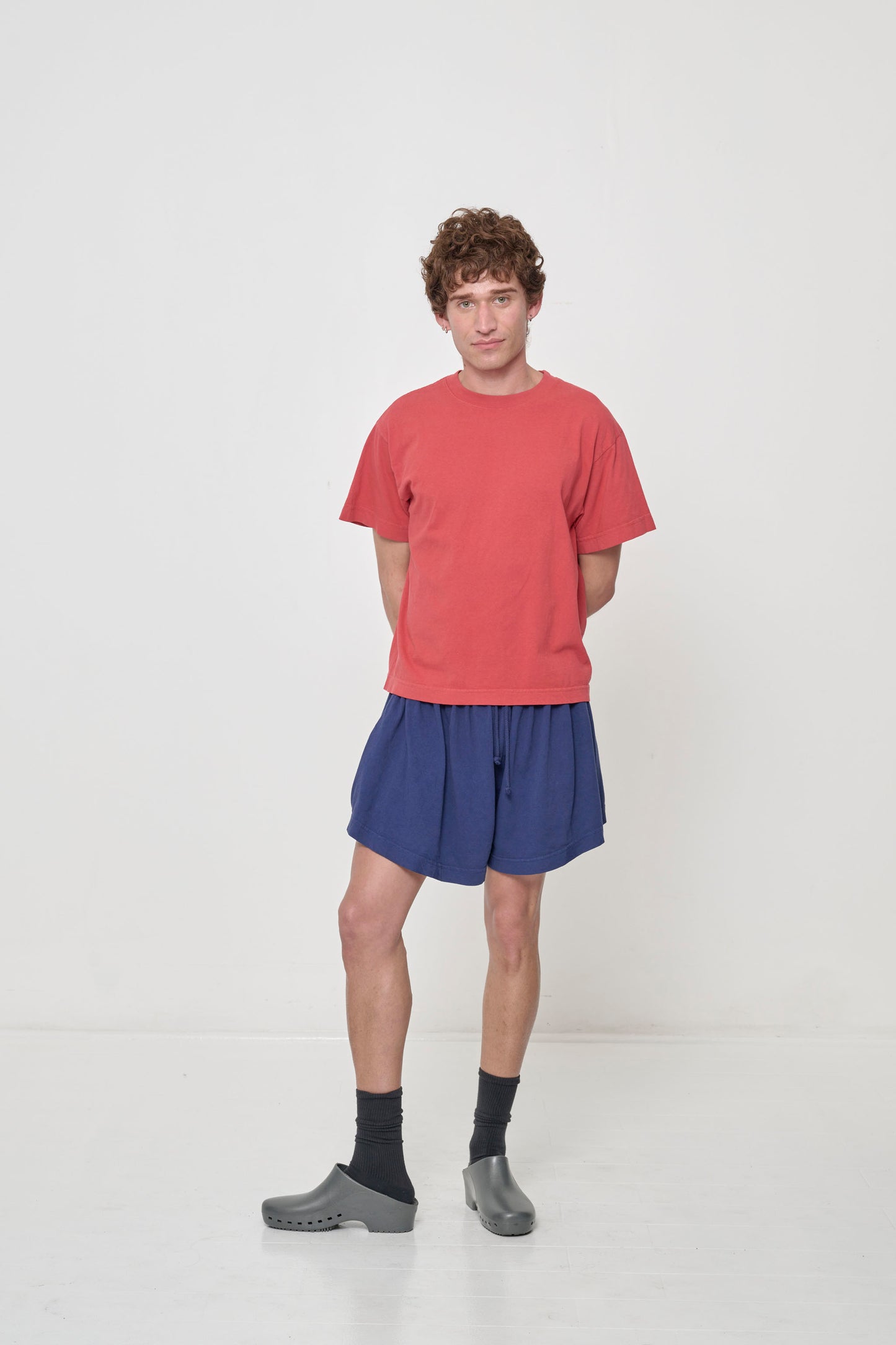 Person in Washed Navy Tubular Shorts, with one knee popped, showing the width and movement of the leg opening.
