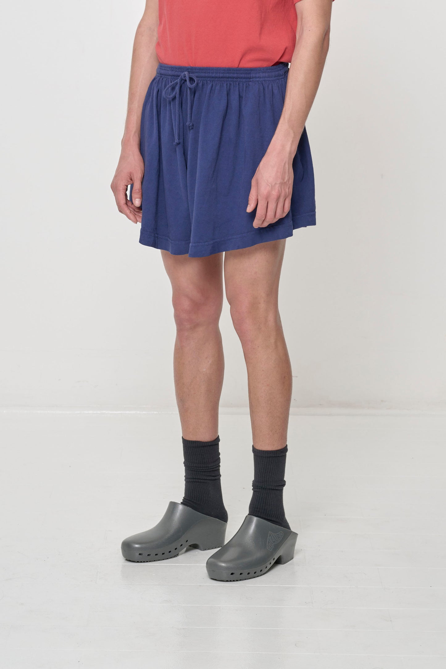 Person facing 45-degrees to the front in Washed Navy Tubular Shorts, showing lack of side seams and shorter side hem.