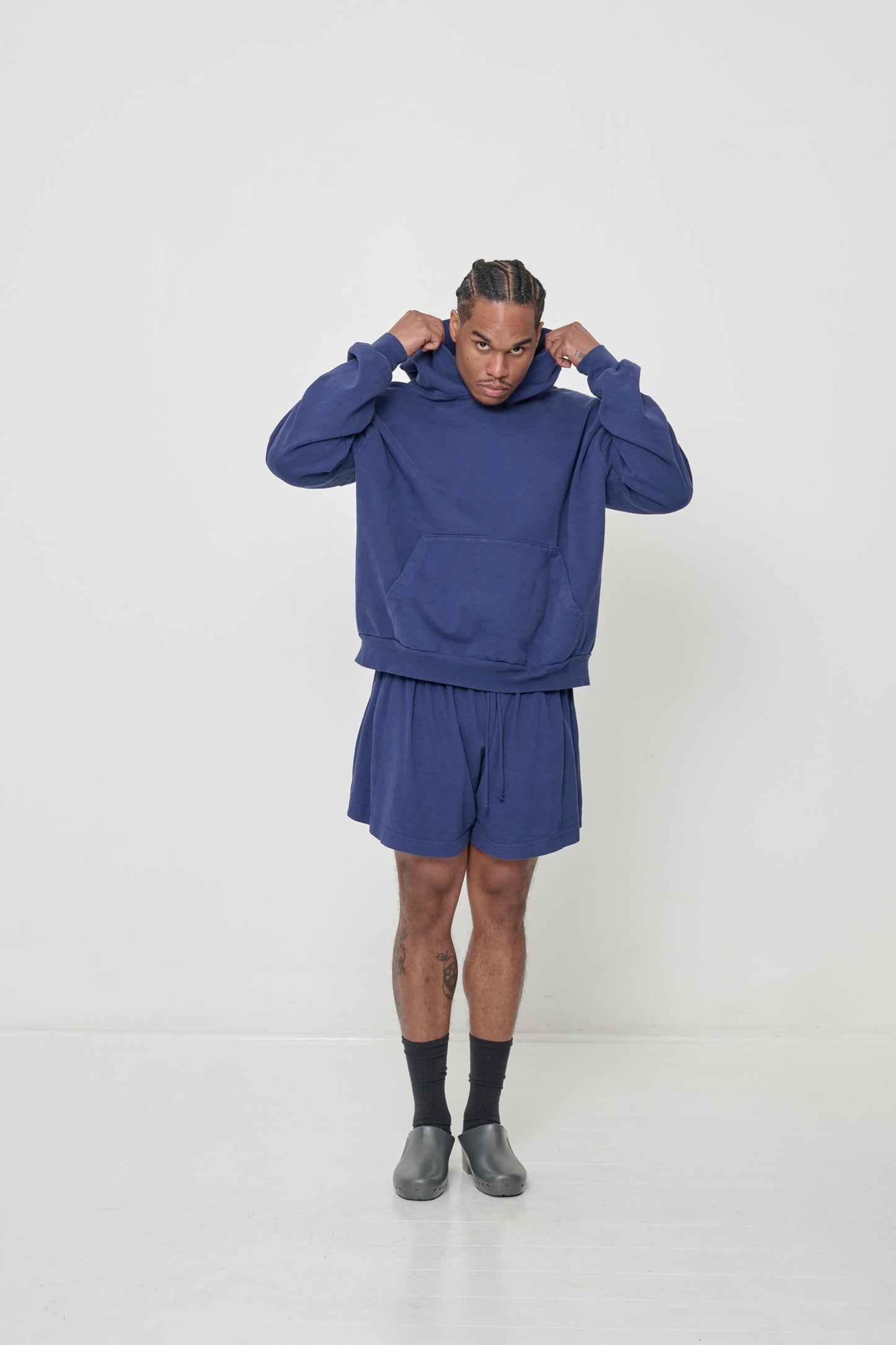 Man in matching Washed Navy Trash Hoodie and Tubular Shorts, Black Squishy Socks and Metallic Grey Calzuro Classic Clogs.