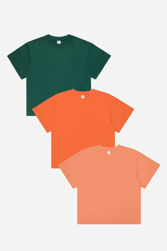 Three t-shirts in green, orange, and peach on a white background