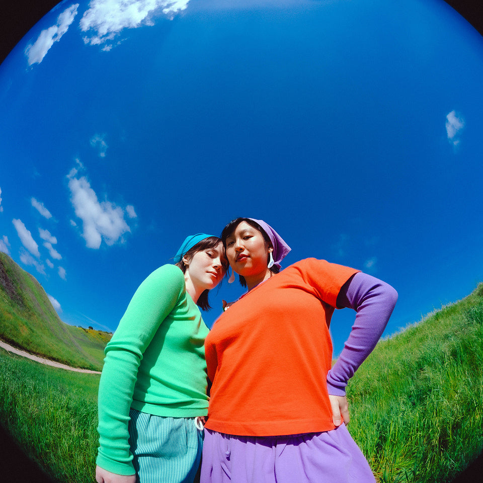 Two people in a field wearing various brightly colored garments from the Everybody.World new collection.