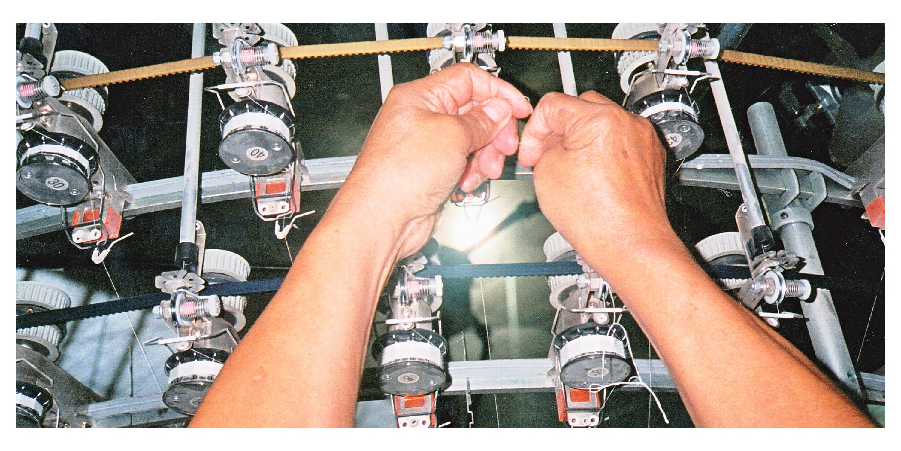 Person operating a machine with multiple spools of thread.
