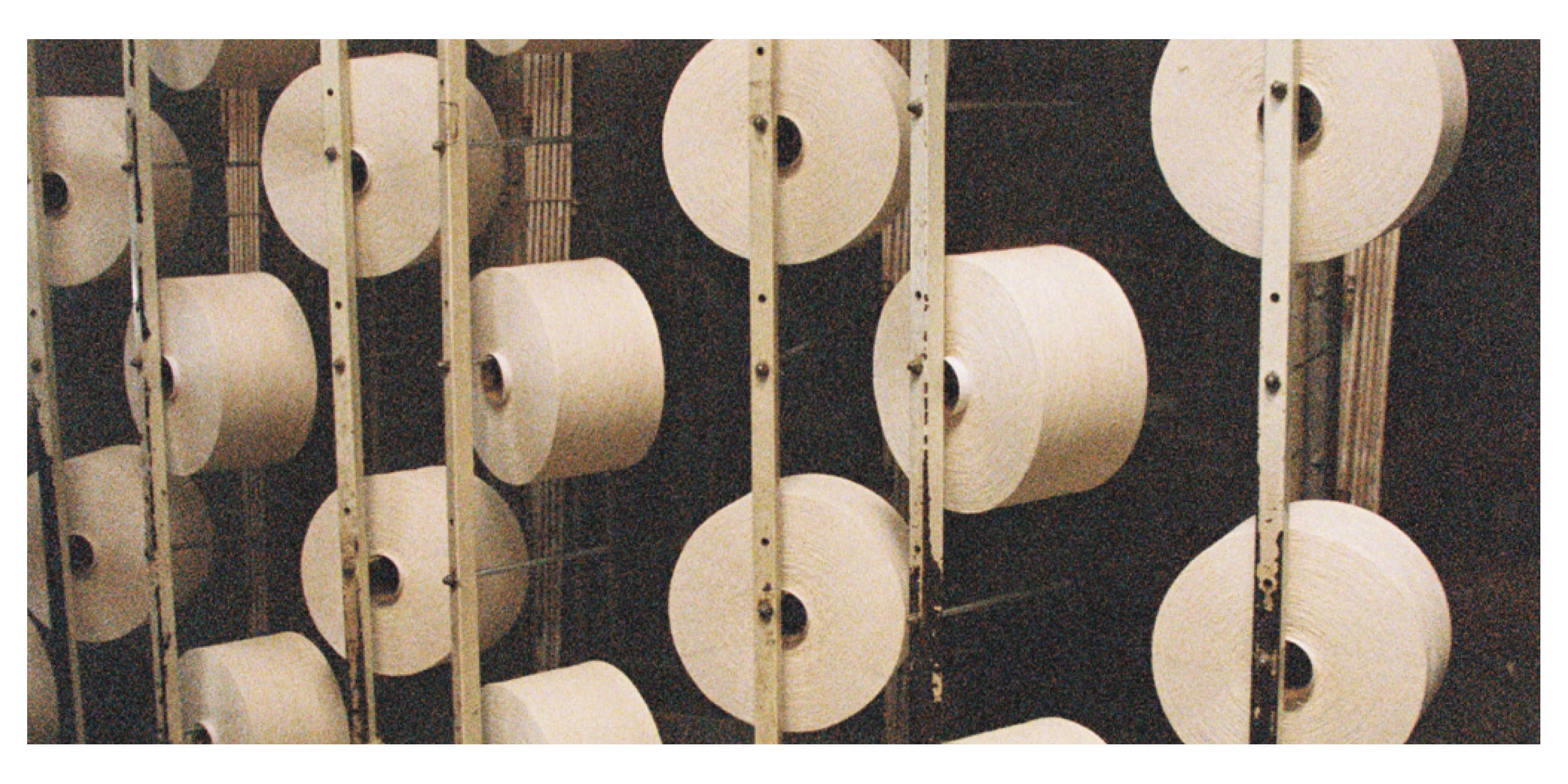 Multiple spools of white cotton thread on a dark background.