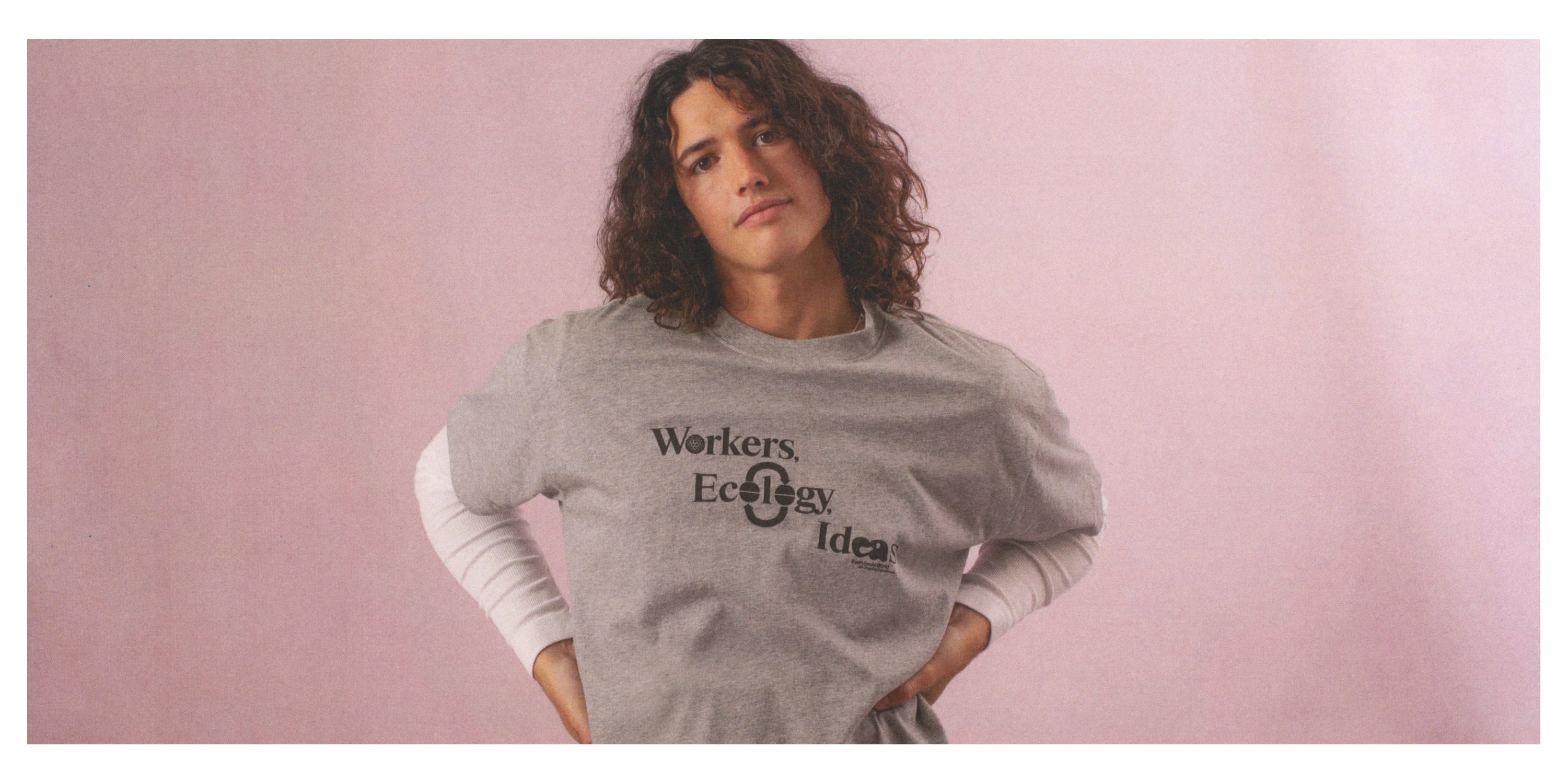 Person wearing a Heather Short Sleeve Tee with text that reads 'Workers, Ecology, Ideas'