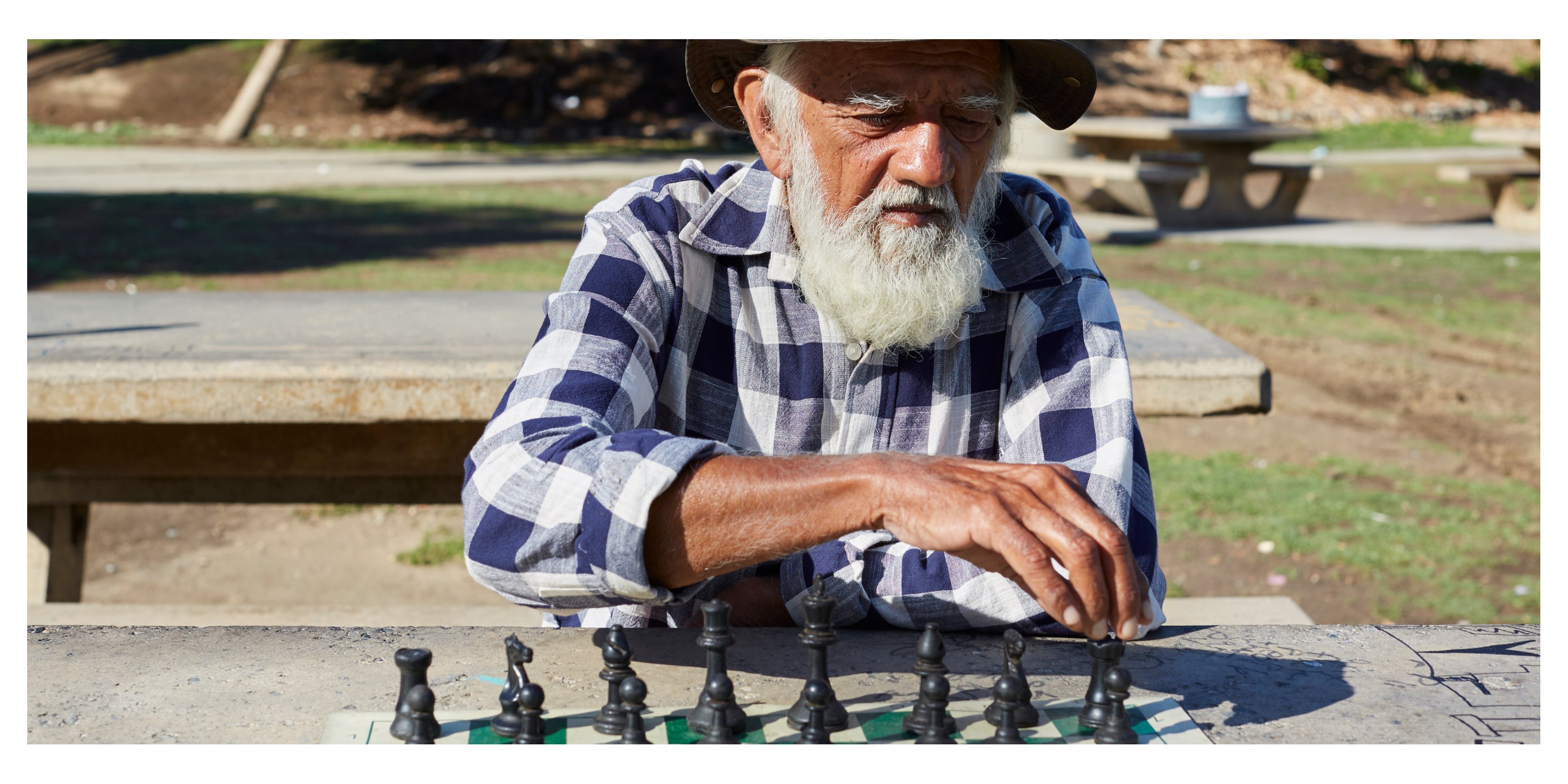 Prakash Gokalchand sits at a table outside playing chess.