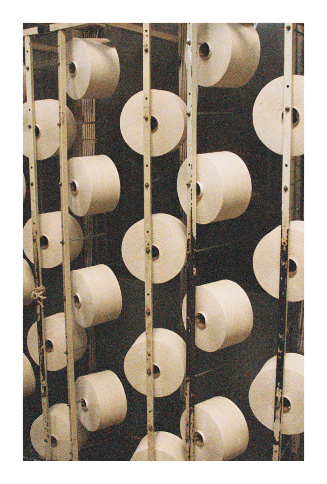 Multiple spools of white cotton thread on a dark background.