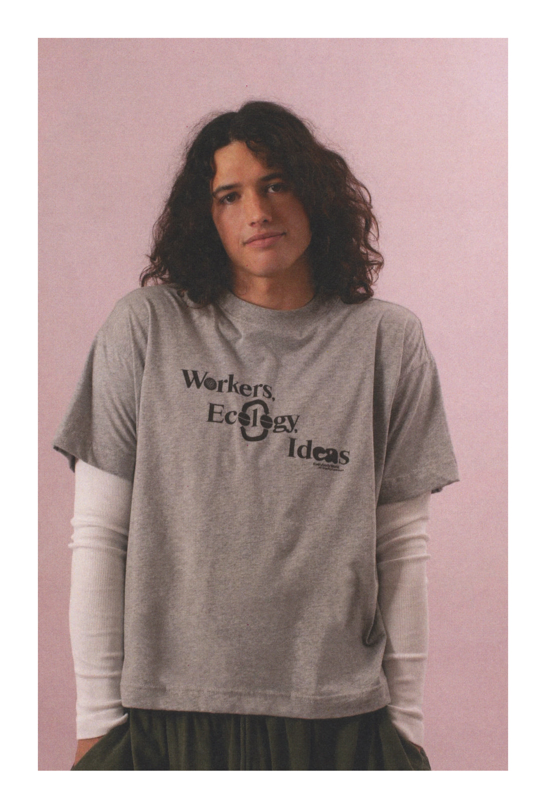 Person wearing a Heather Short Sleeve Tee with text that reads 'Workers, Ecology, Ideas'