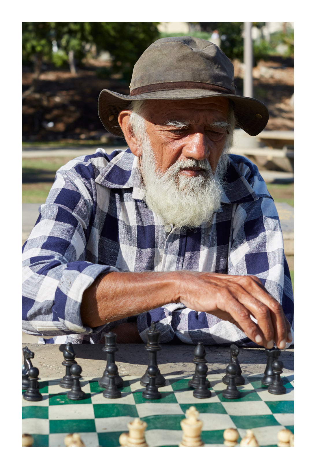 Prakash Gokalchand sits at a table outside playing chess.