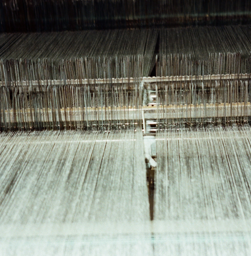 A close-up of a weaving machine with a pile of yarn