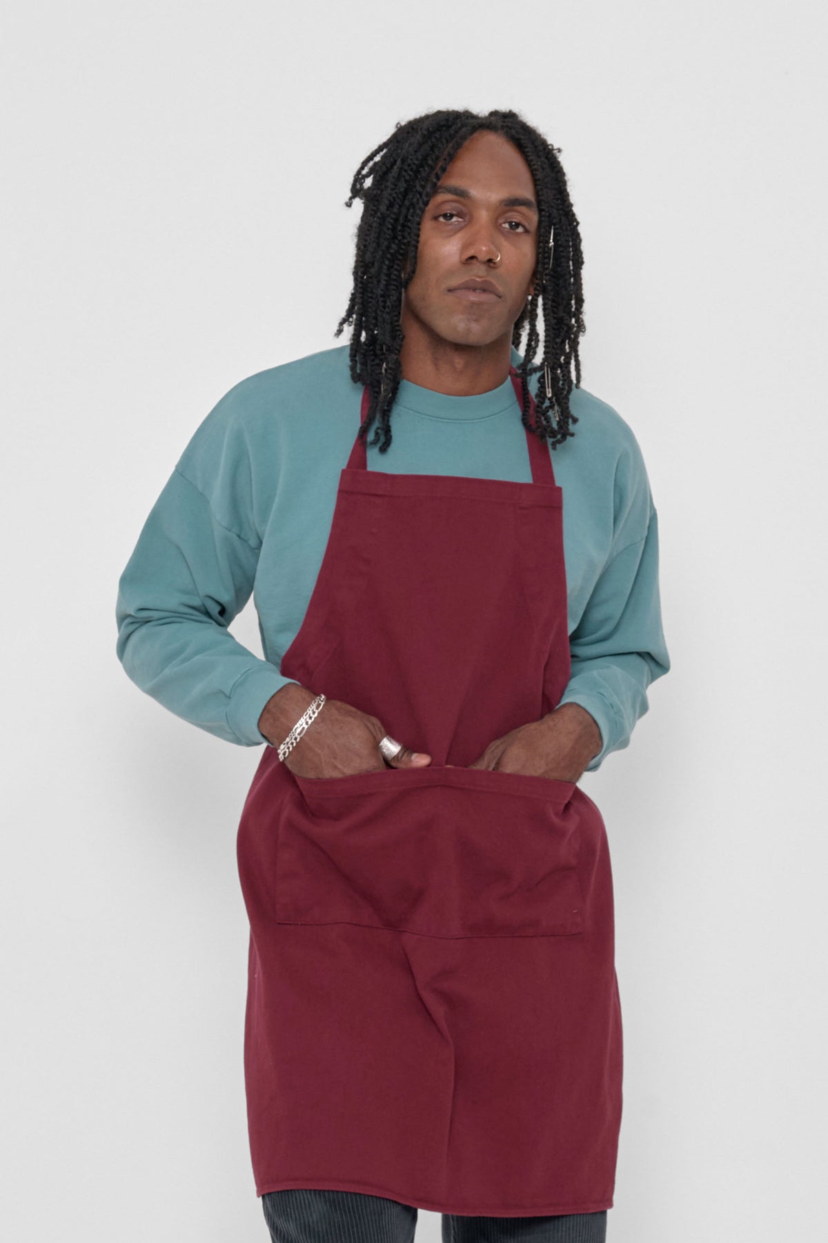 Adjustable Apron in Garnet – front view, model's hands in each of 2 front pockets at hip height