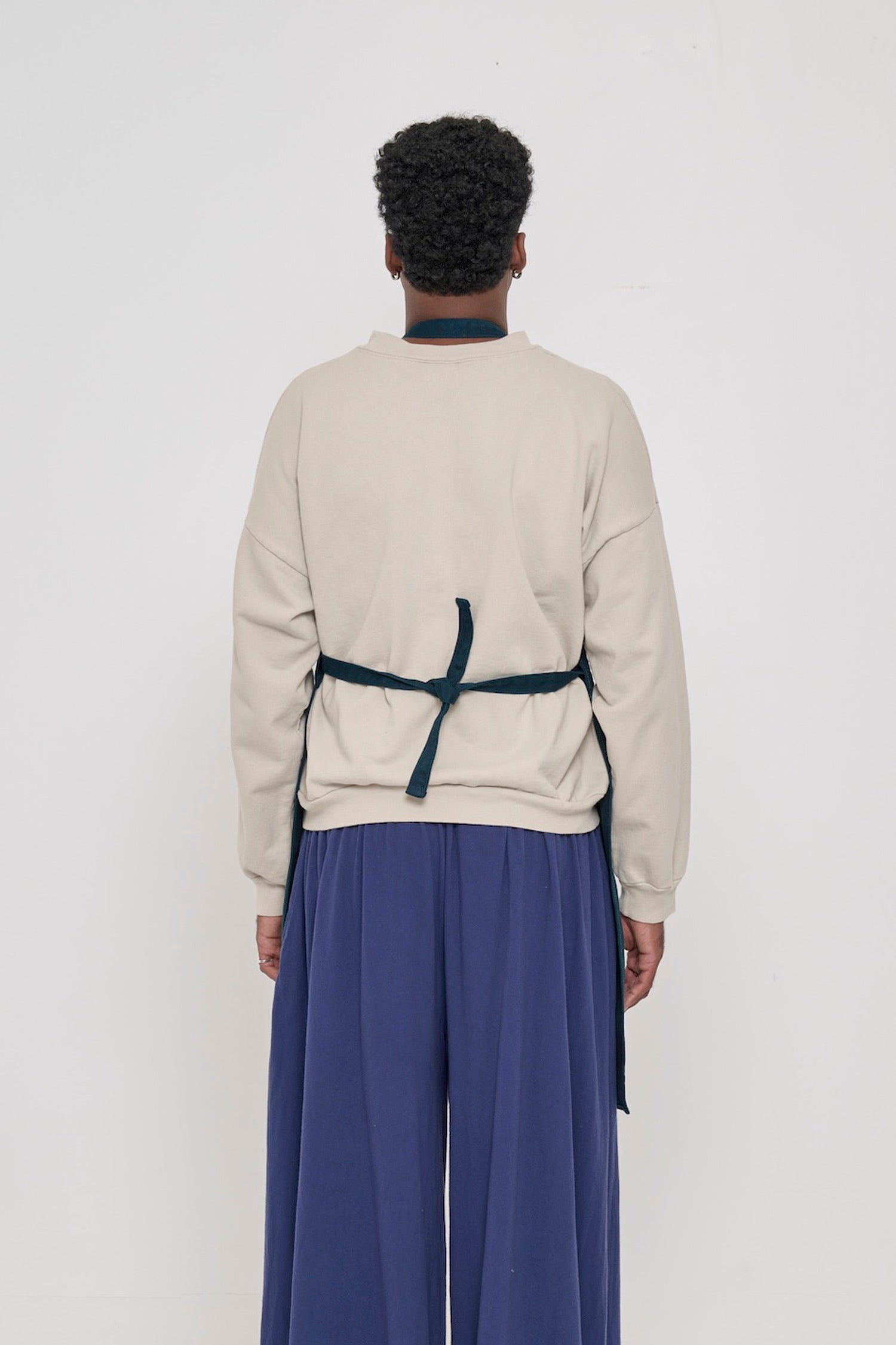 Rear view of a person in a Juniper Adjustable Apron, showing the neck loop and waist straps tied.