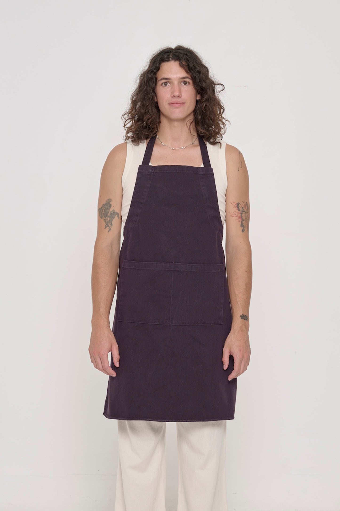 Front view of a person in an Adjustable Apron in Mulberry, with straps tied behind their back.