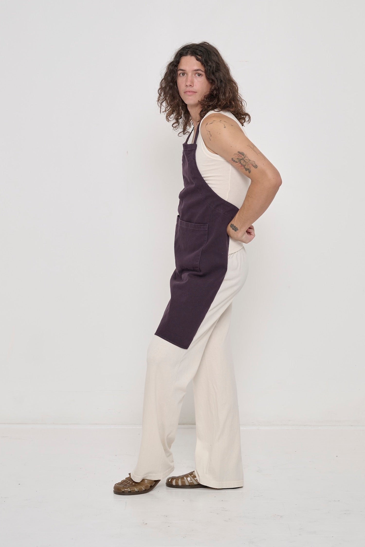 Mulberry Adjustable Apron on a person, covering chest to knees, photographed from the side, hands holding back ties.