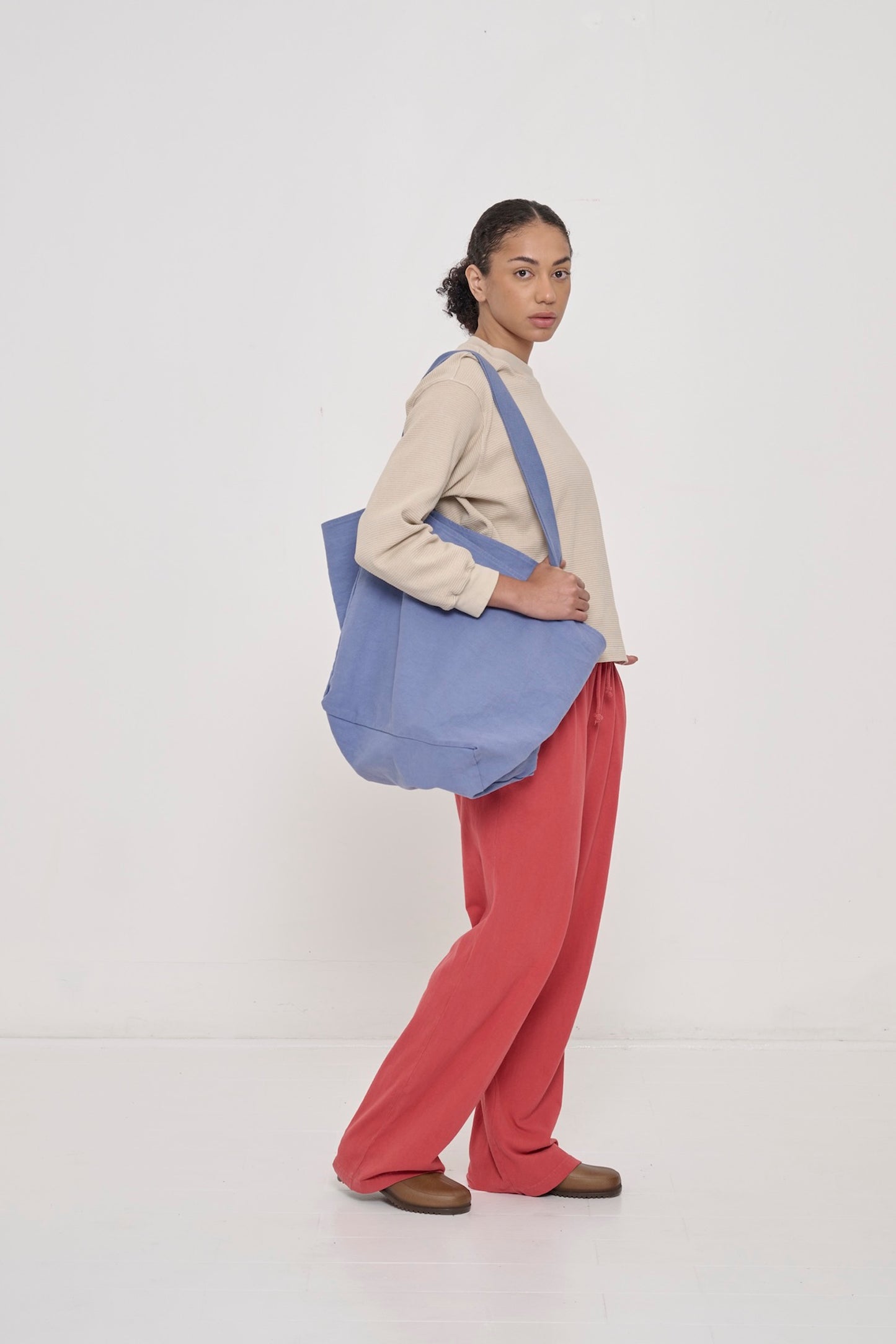 A woman wearing Jerico's Apartment Pants in Cedar and carrying the Periwinkle Big Tote.