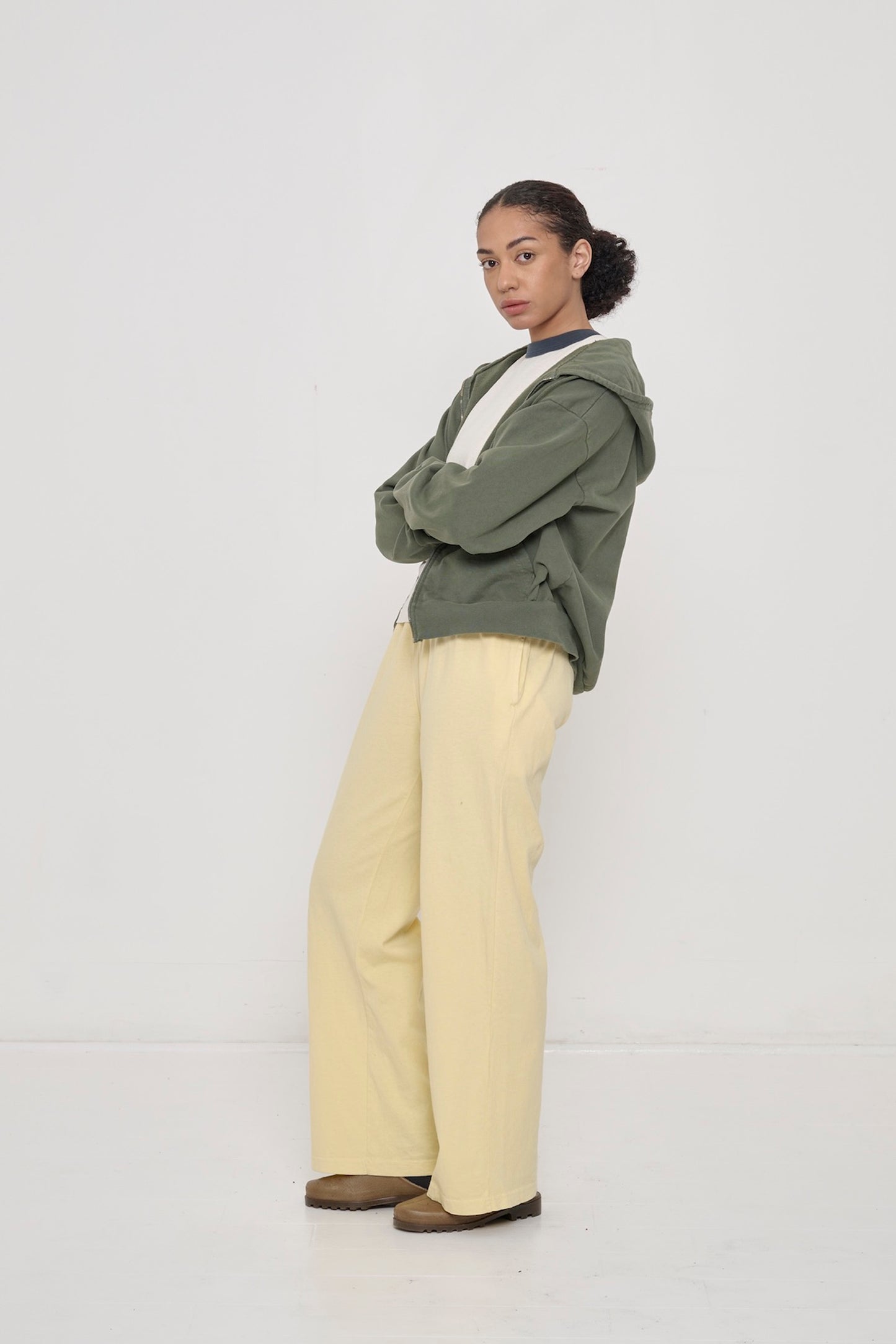 Profile: woman in French Butter Apartment pants. Leaning back with a popped knee, showing inseam, outseam, and side pocket.