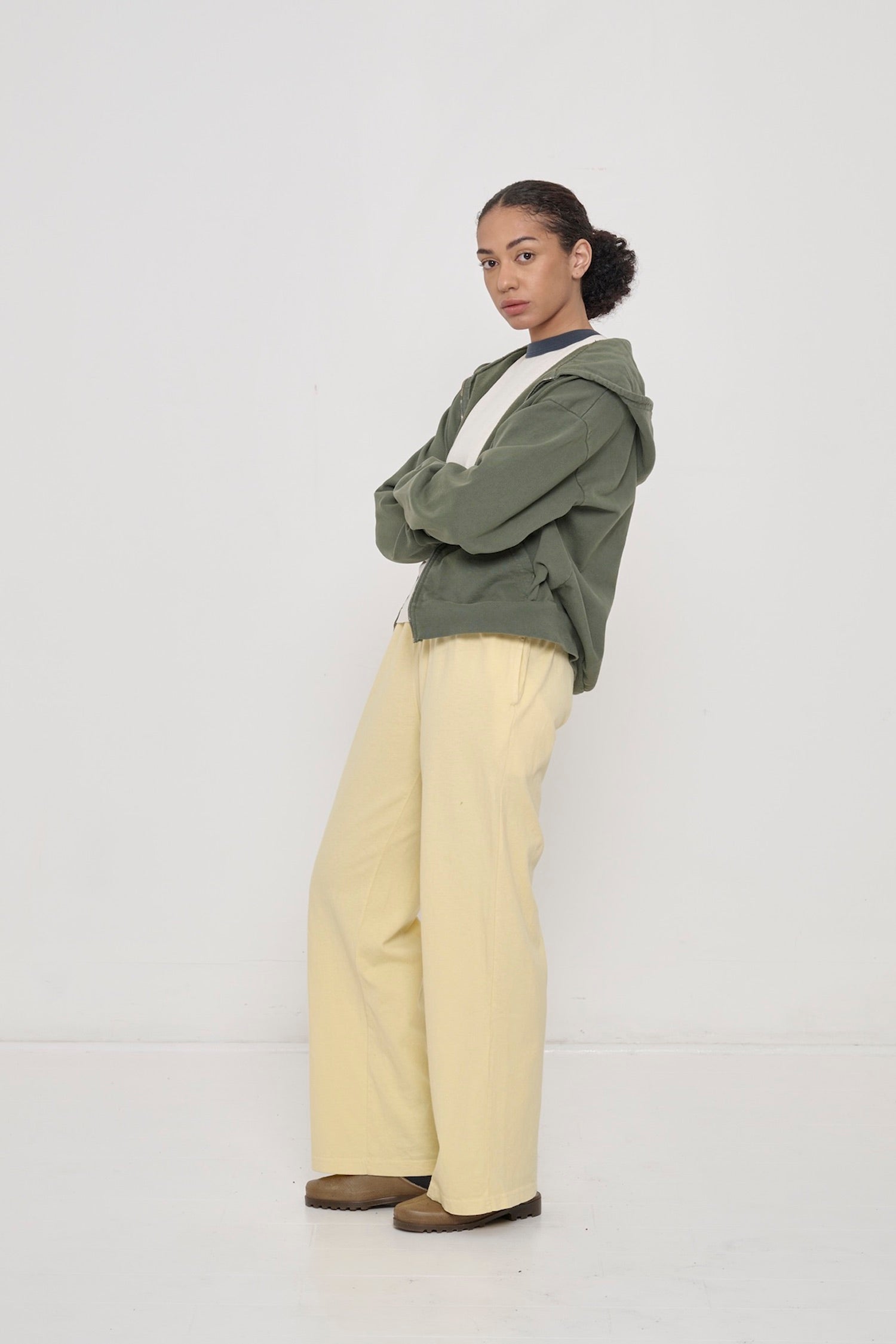 Profile: woman in French Butter Apartment pants. Leaning back with a popped knee, showing inseam, outseam, and side pocket.