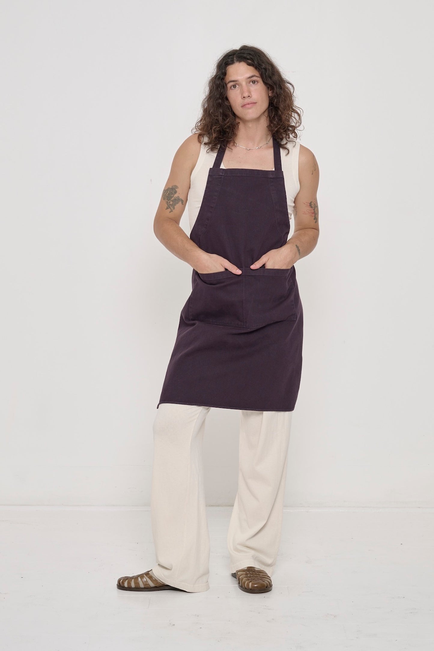 Person wearing a Mulberry Adjustable Apron over matching Scour The Tank and Apartment Pants. Hands in apron pockets. 