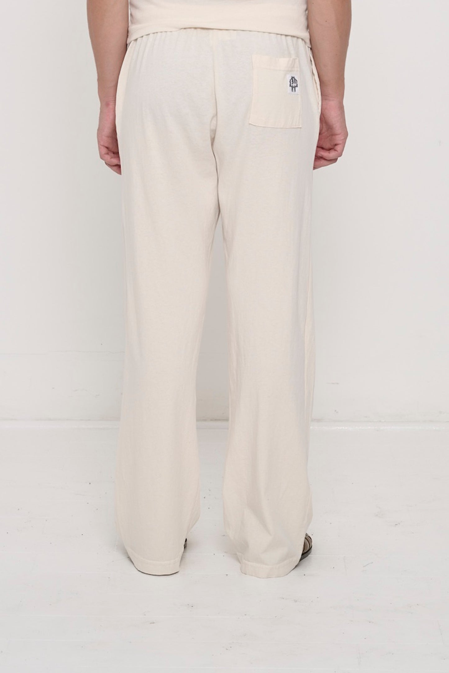 Back view, waist down: a person in Scour Apartment Pants, highlighting the E.W logo printed on the back right pocket.