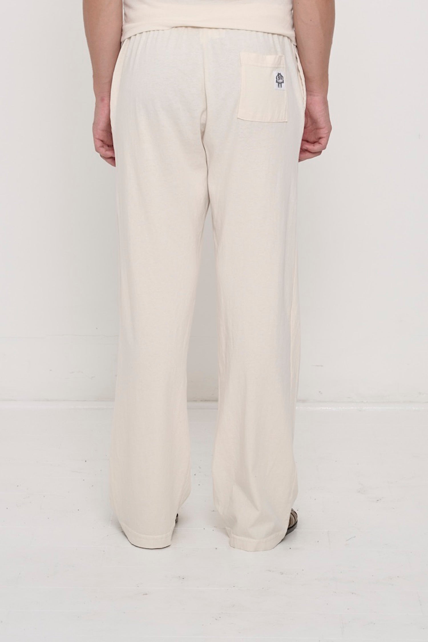 Back view, waist down: a person in Scour Apartment Pants, highlighting the E.W logo printed on the back right pocket.