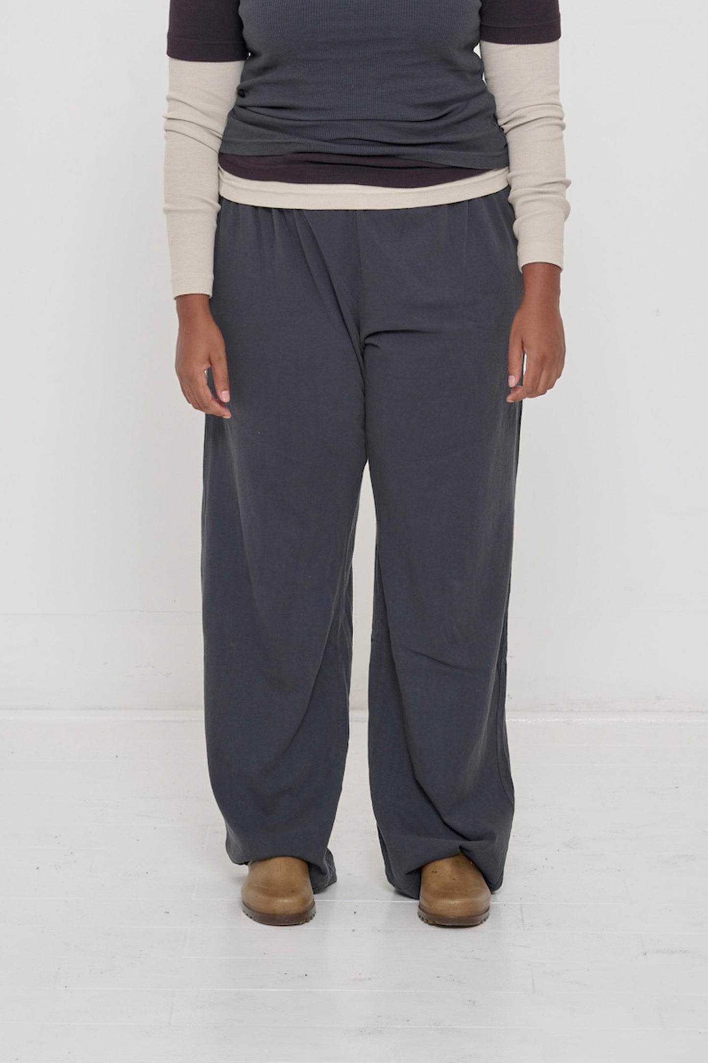 Close-up front view of a person wearing Slate Apartment Pants, showing relaxed drape, loose through the leg.