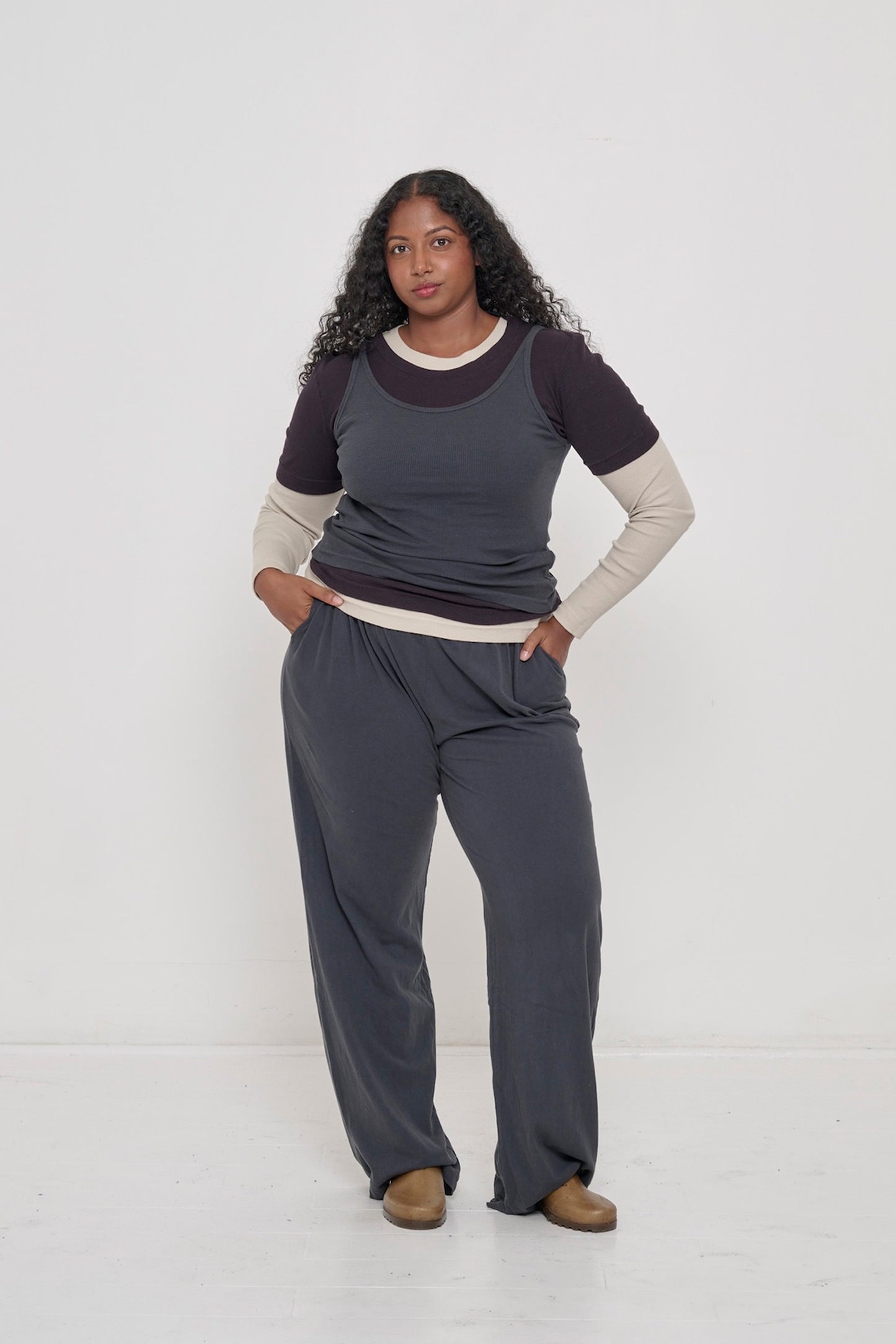 A person wearing  Apartment Pants in Slate with the Slate Rib Tank. Both hands in the front pockets show a relaxed fit.