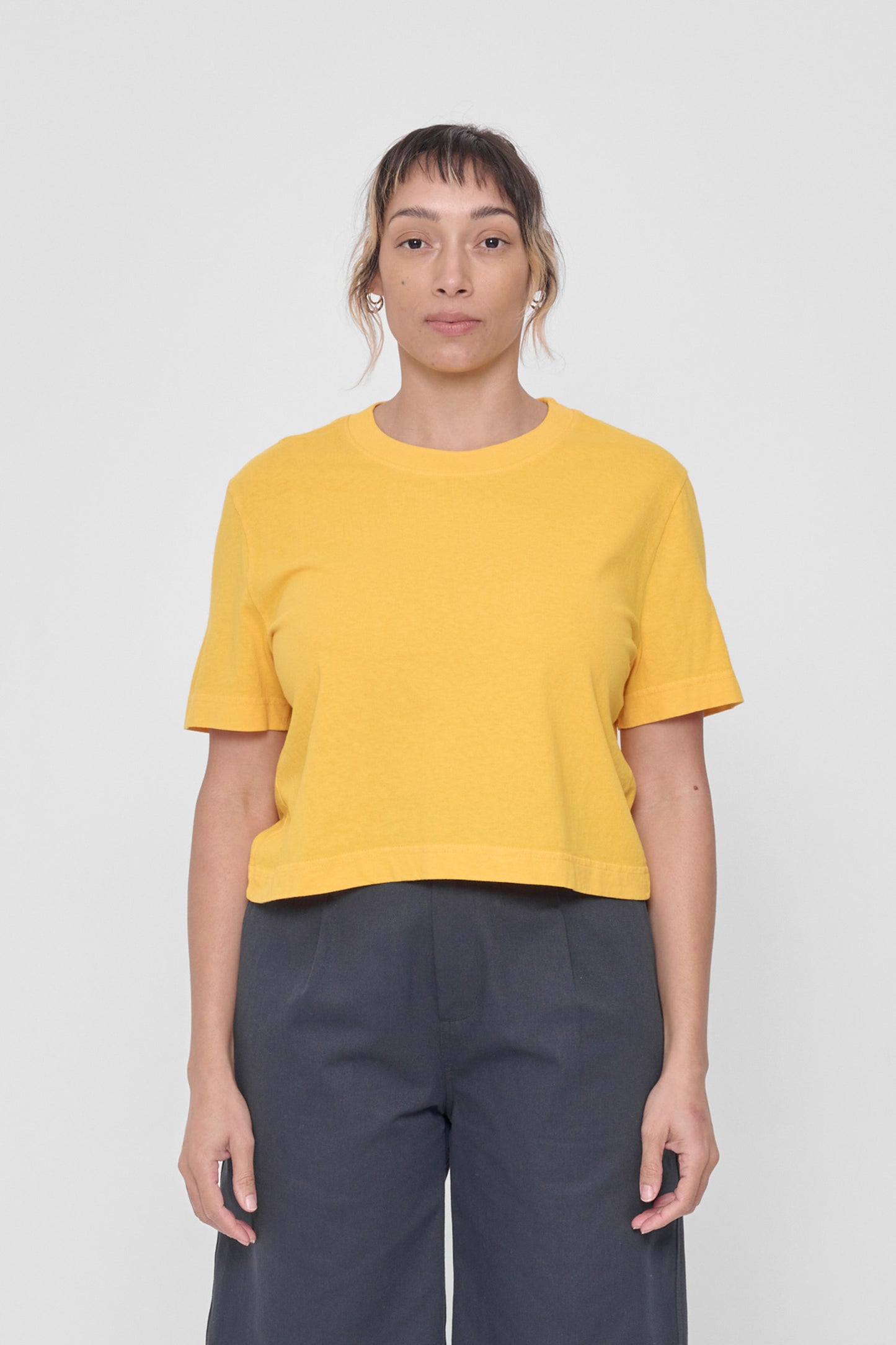 Front view of 5'4" woman wearing size L Everybody Yellow Baby Trash Tee. Hem hits at her navel. 