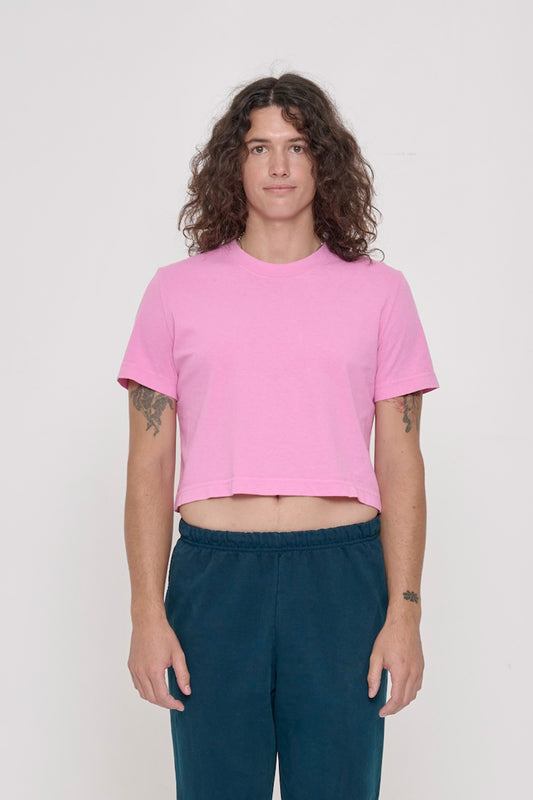 Person wearing light pink cropped t-shirt with dark blue pants. Band of stomach is visible.