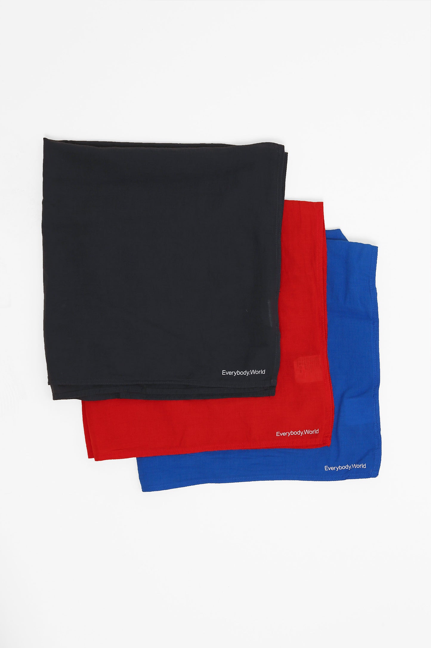 Flat lay of three folded bandanas in Slate, Lava, and Lapis, featuring Everybody.World branding on a gray background