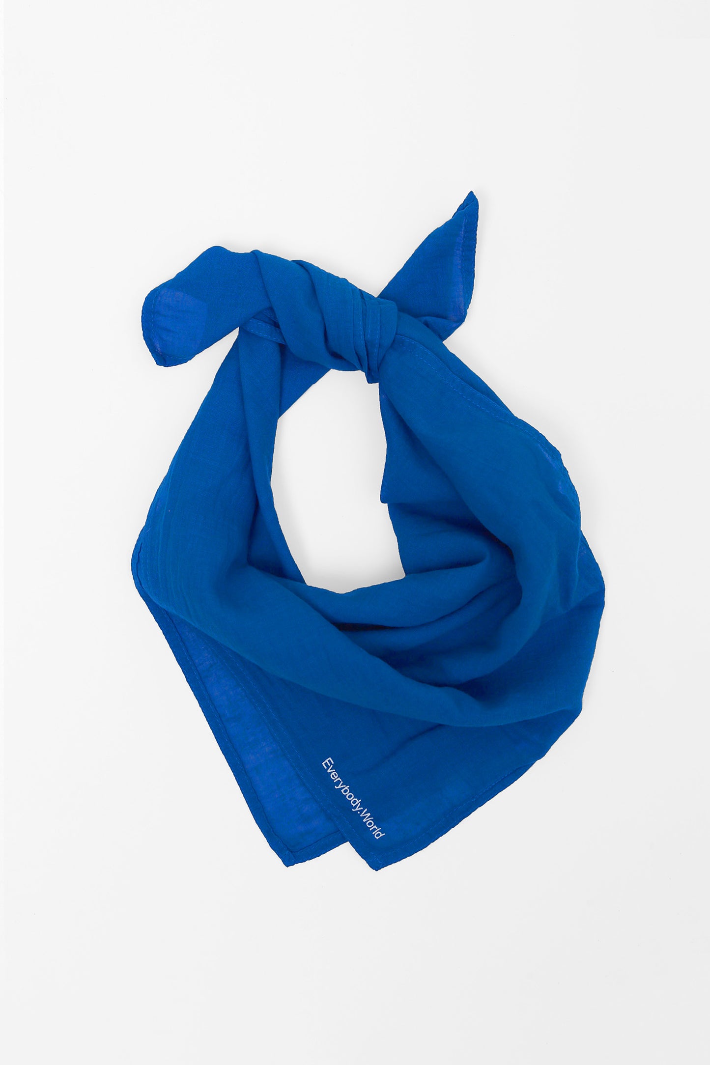 Lapis colored scarf tied in a knot on a light gray background.